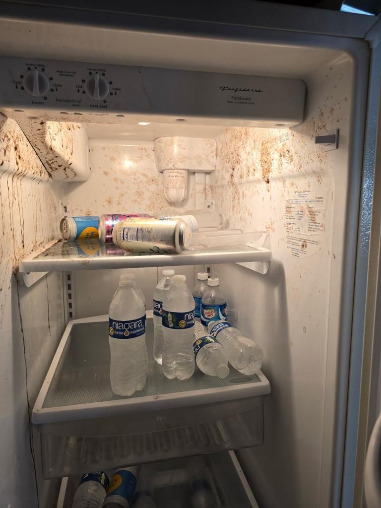 Person in blue overalls operates a gray and yellow commercial vacuum cleaner on a tile floor in an office.