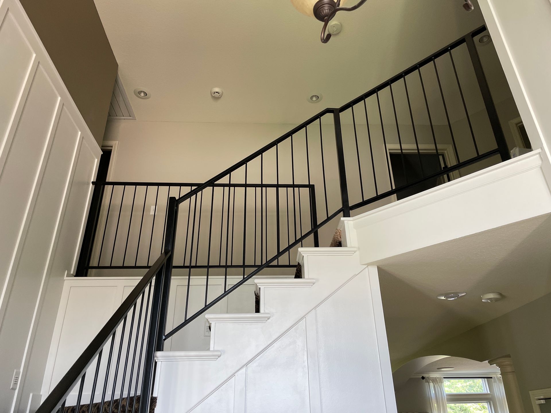 A staircase with a black railing leading up to the second floor of a house.