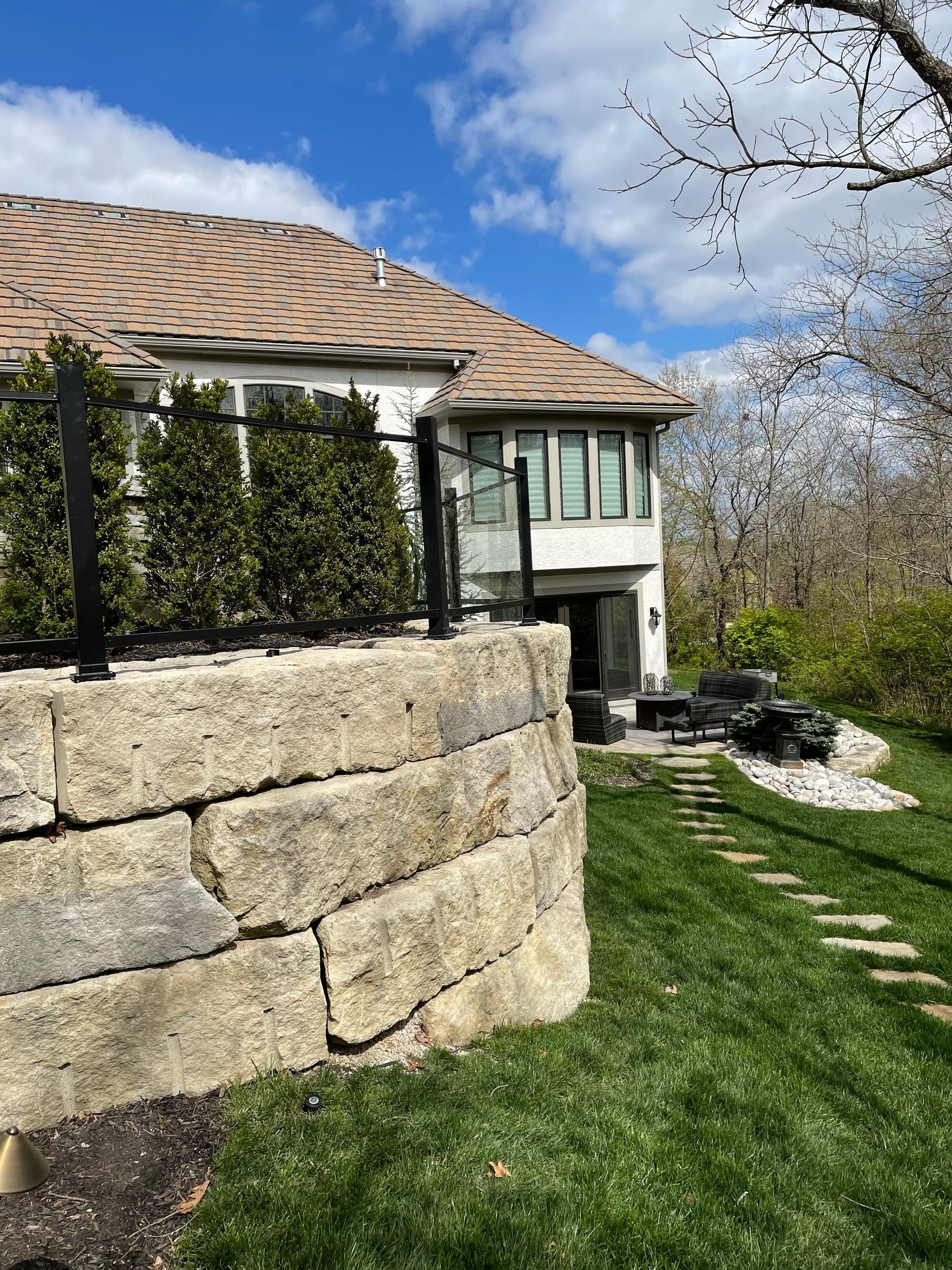 A large house with a stone wall in front of it and black railing on top