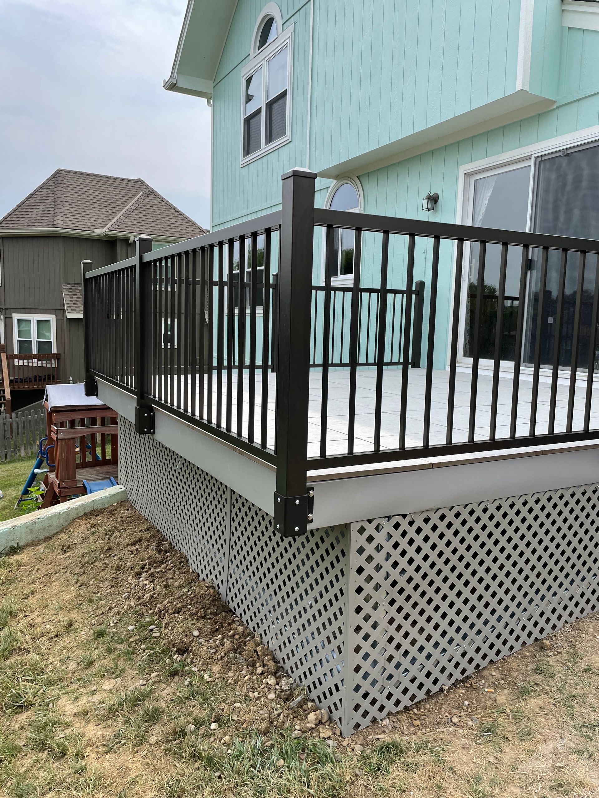 A deck with a black railing is sitting on the side of a house.