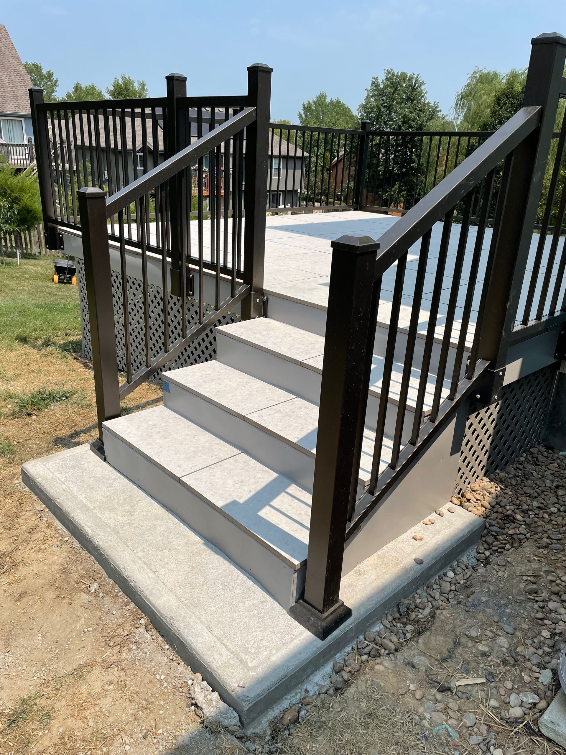 A set of stairs leading up to a deck with a black railing