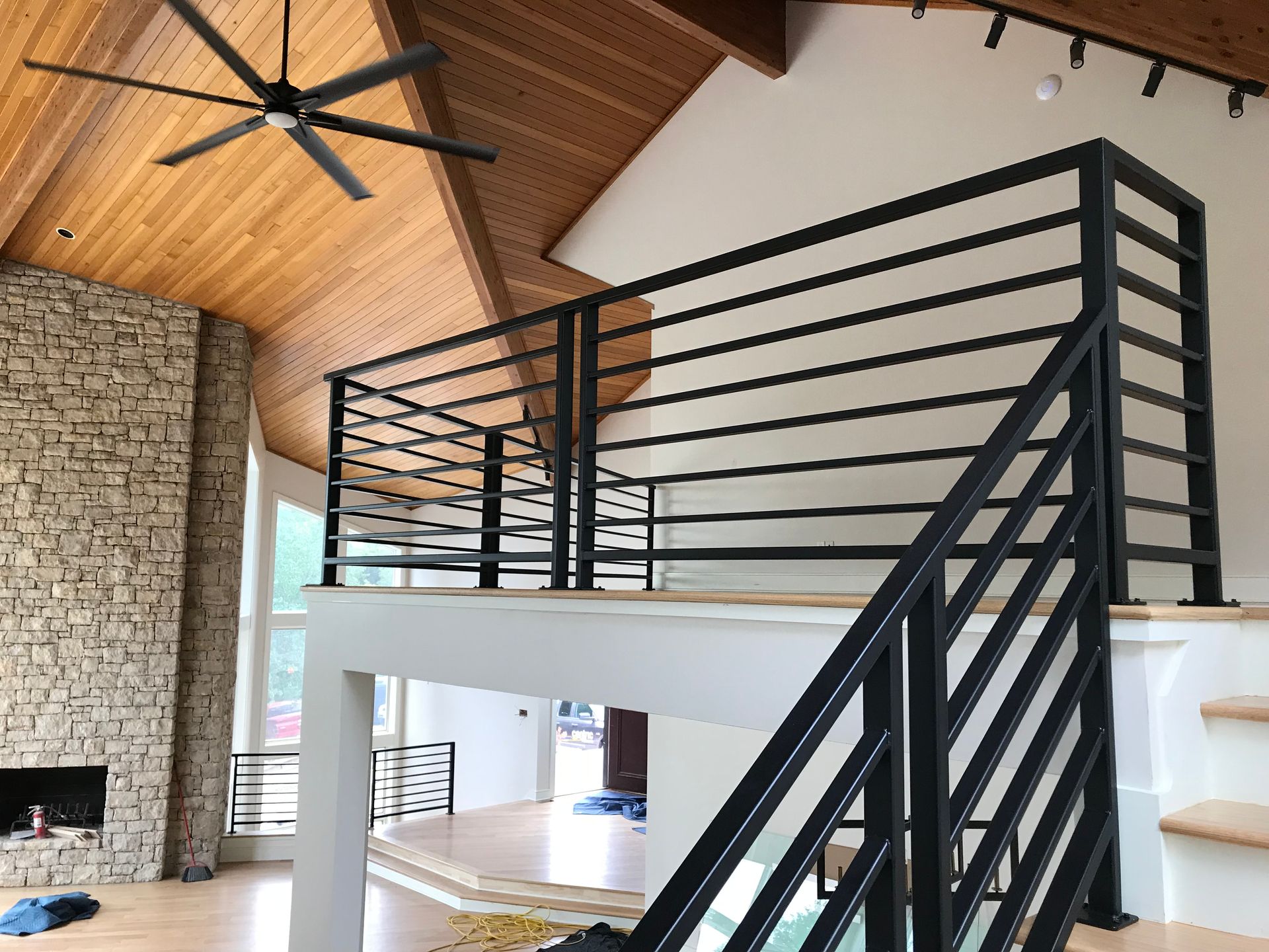 A staircase in a house with a black railing and a ceiling fan.