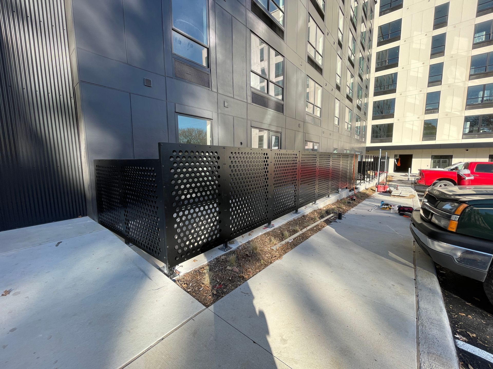 A building with a fence in front of it and a red truck parked in front of it.