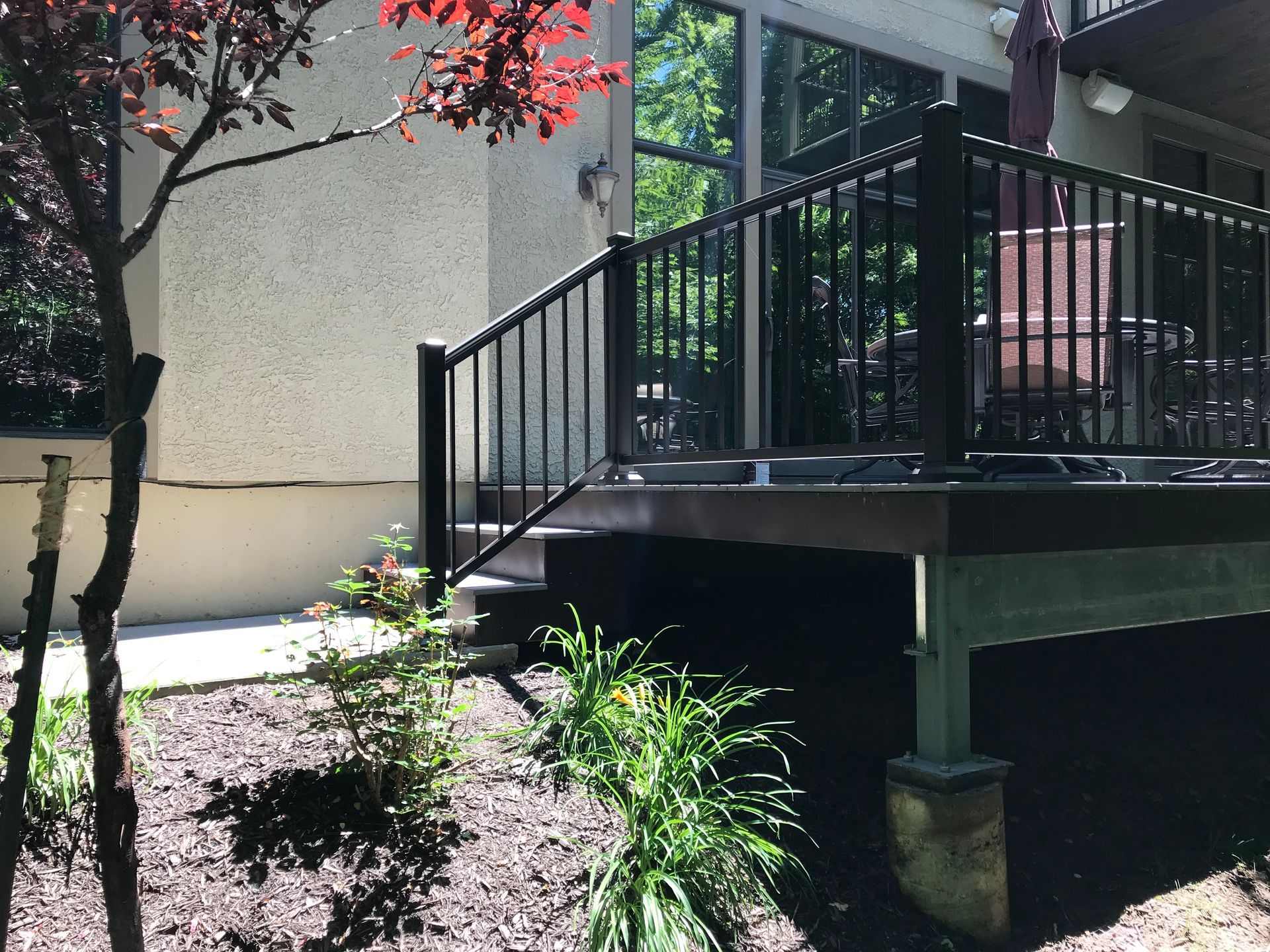 A deck with a railing and stairs in front of a house.