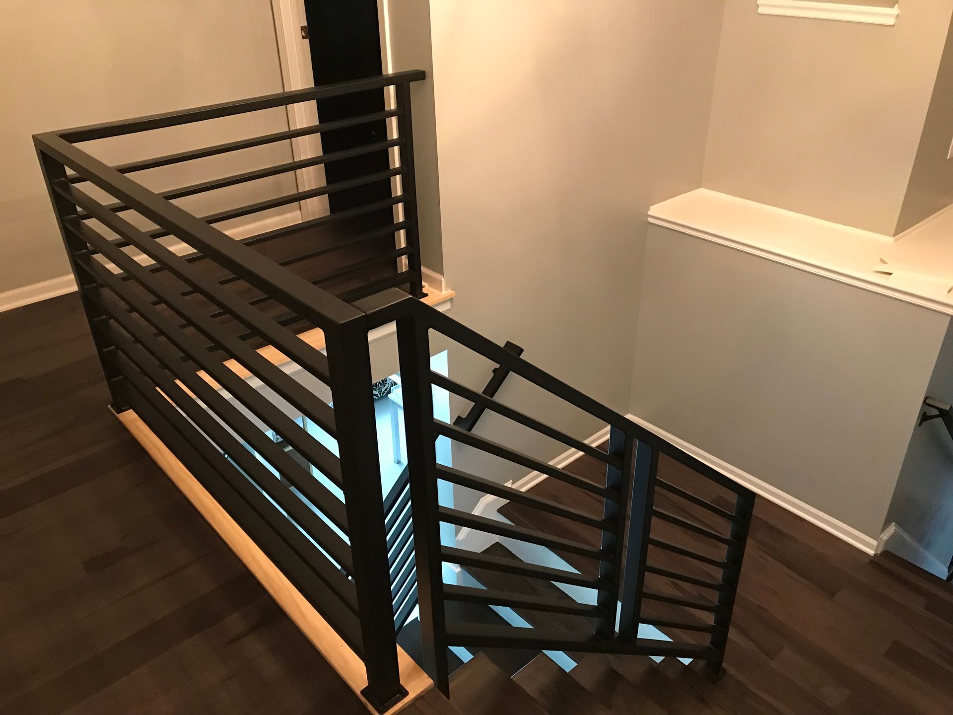 A staircase with a black railing and wooden steps in a house.
