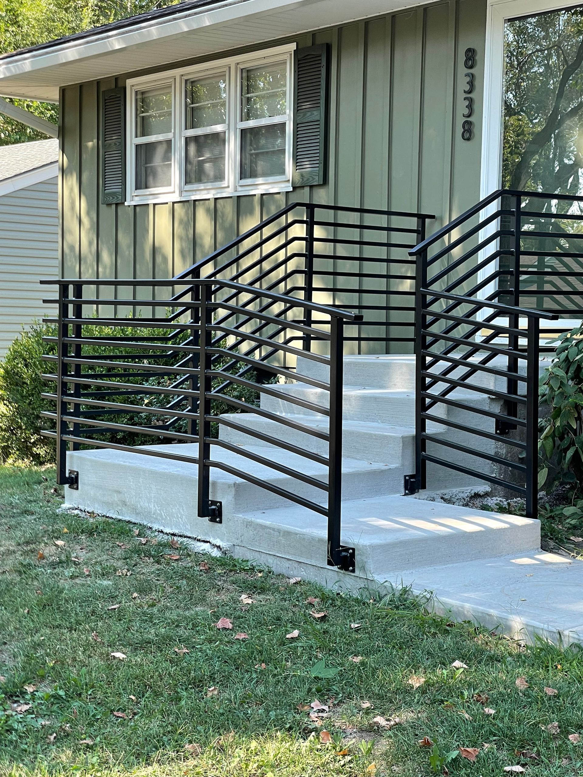 A house with a metal railing and stairs in front of it.