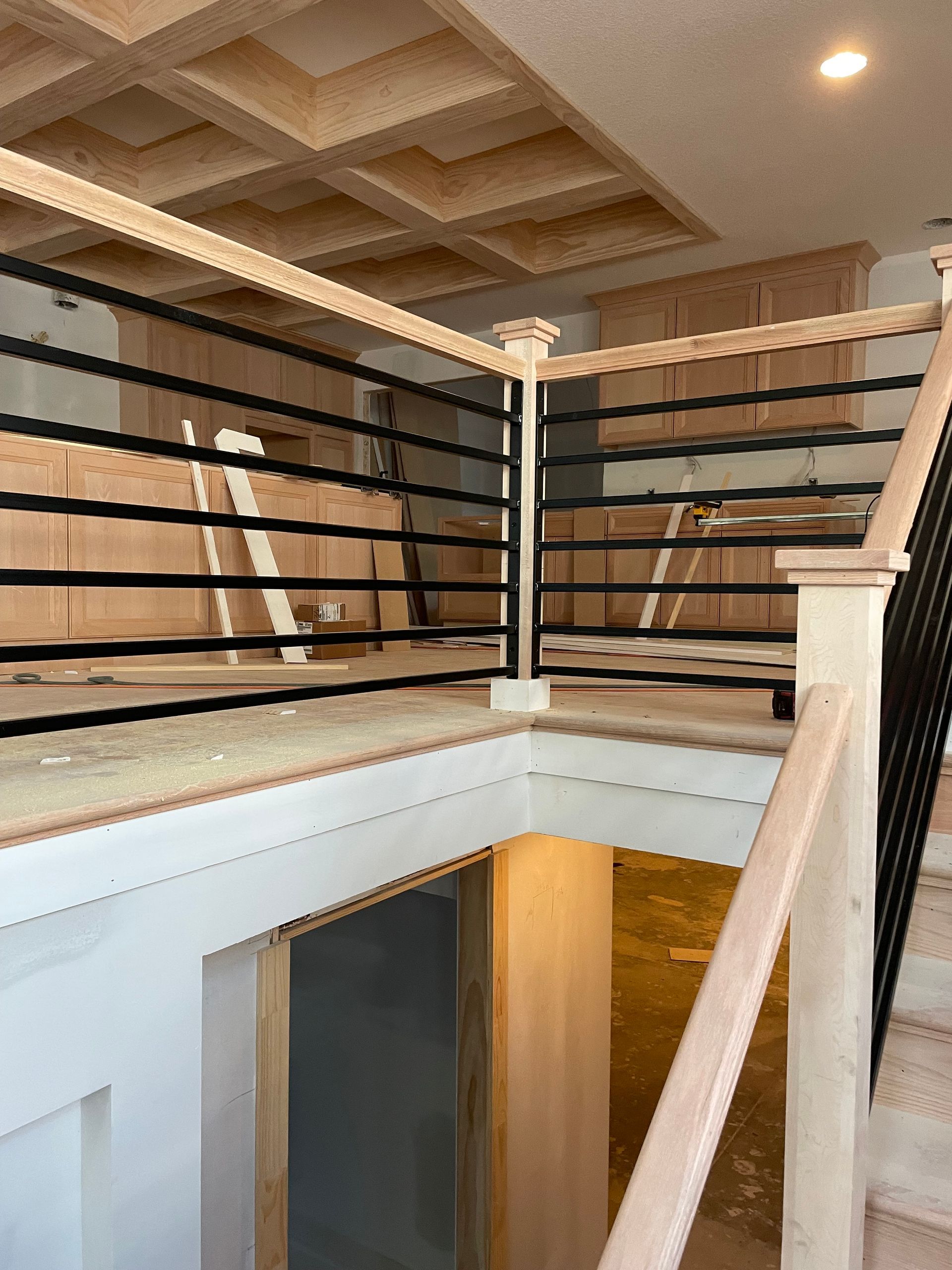 A staircase with a wooden railing and a metal railing in a house under construction.
