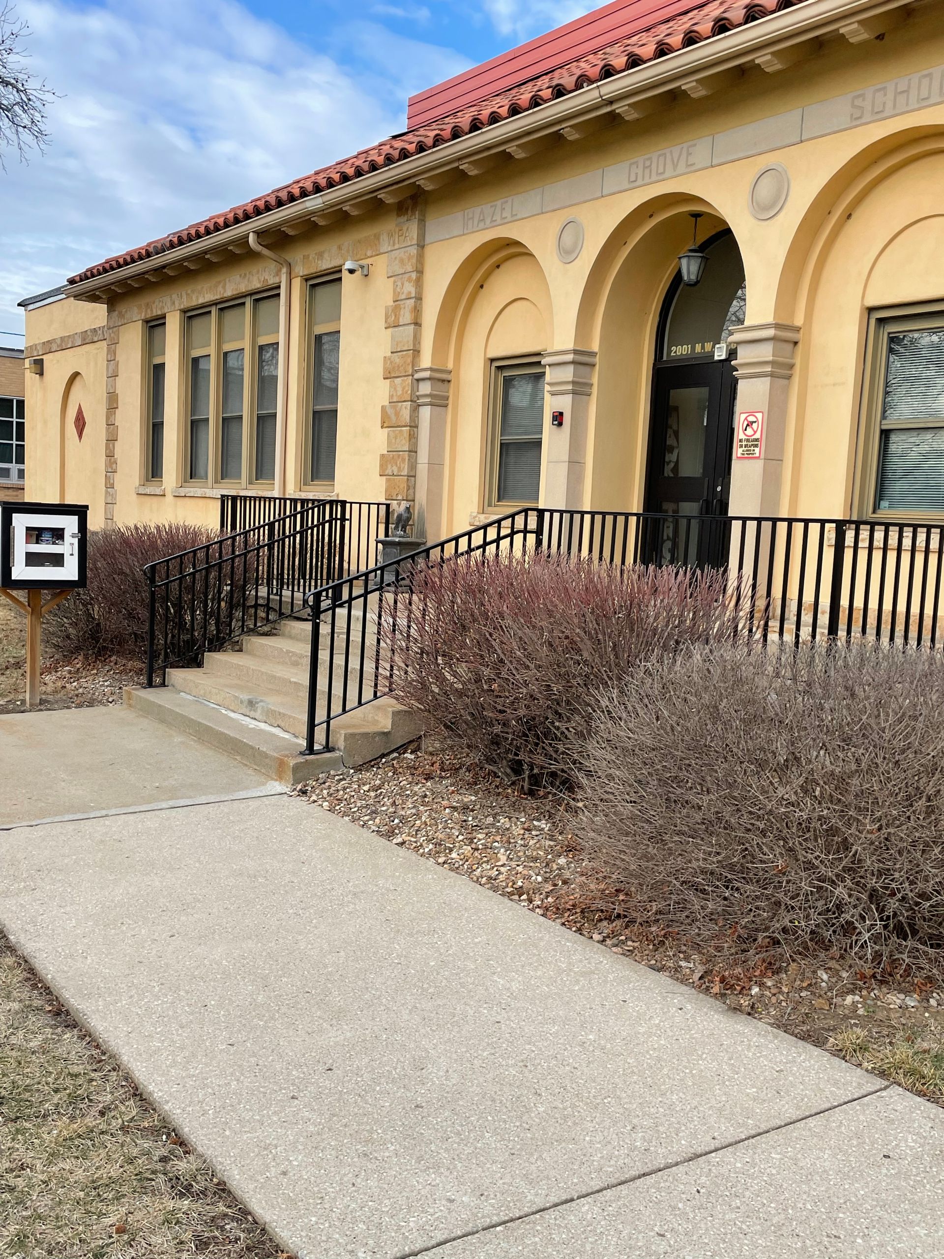 A yellow building with black railings,  arches and a red roof