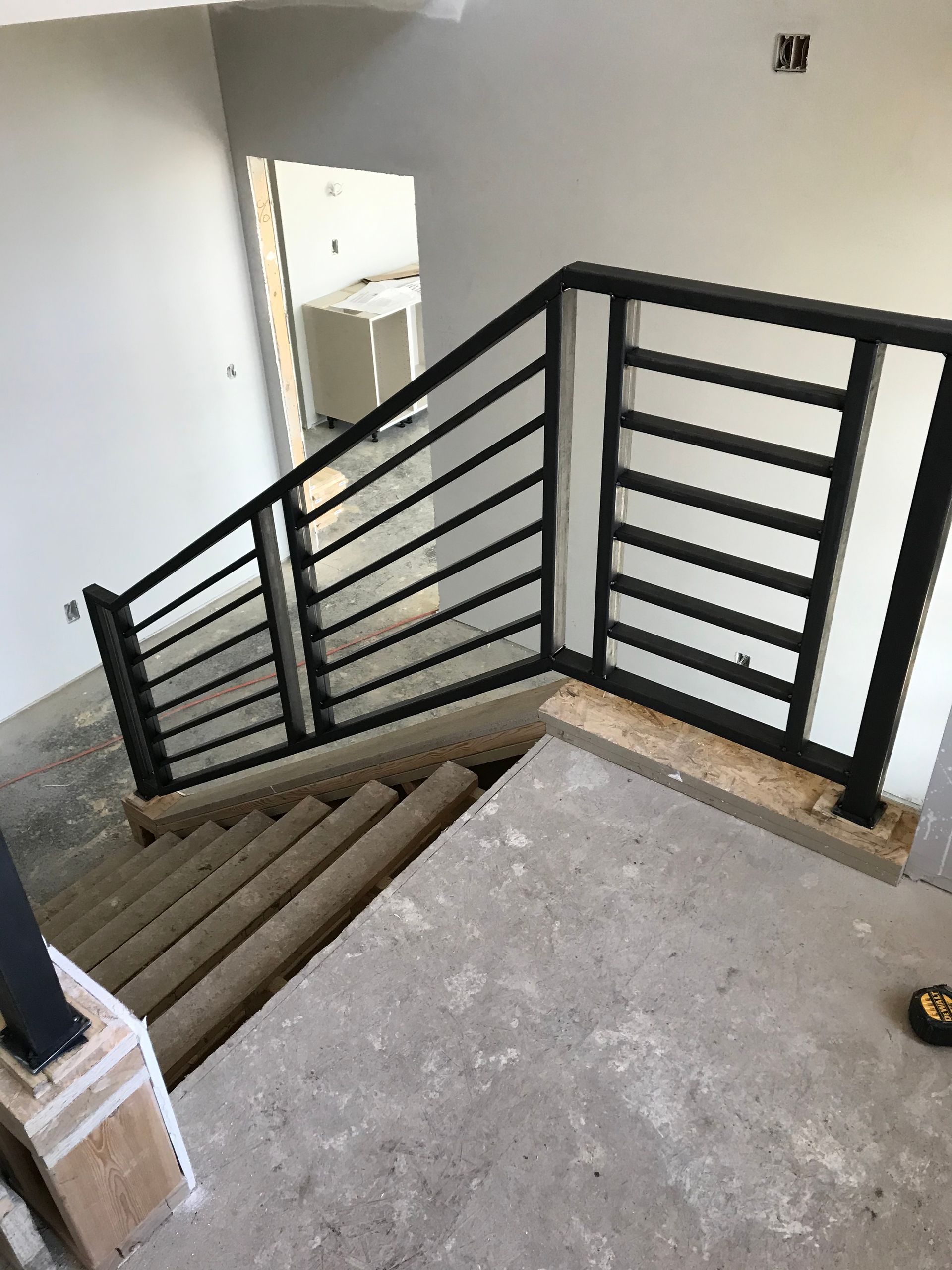 A staircase with a black railing in a building under construction.