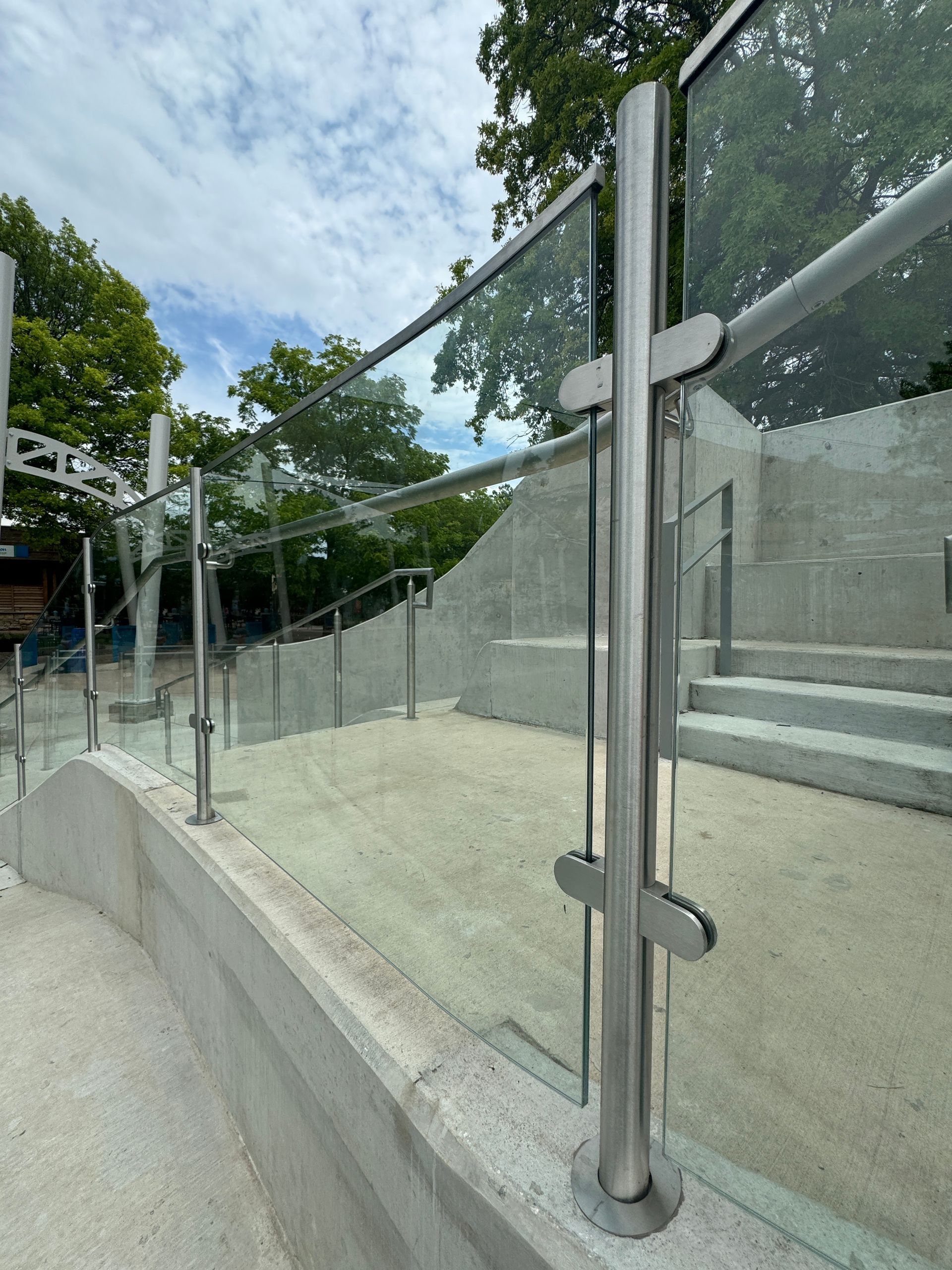A close up of a glass railing with stairs in the background