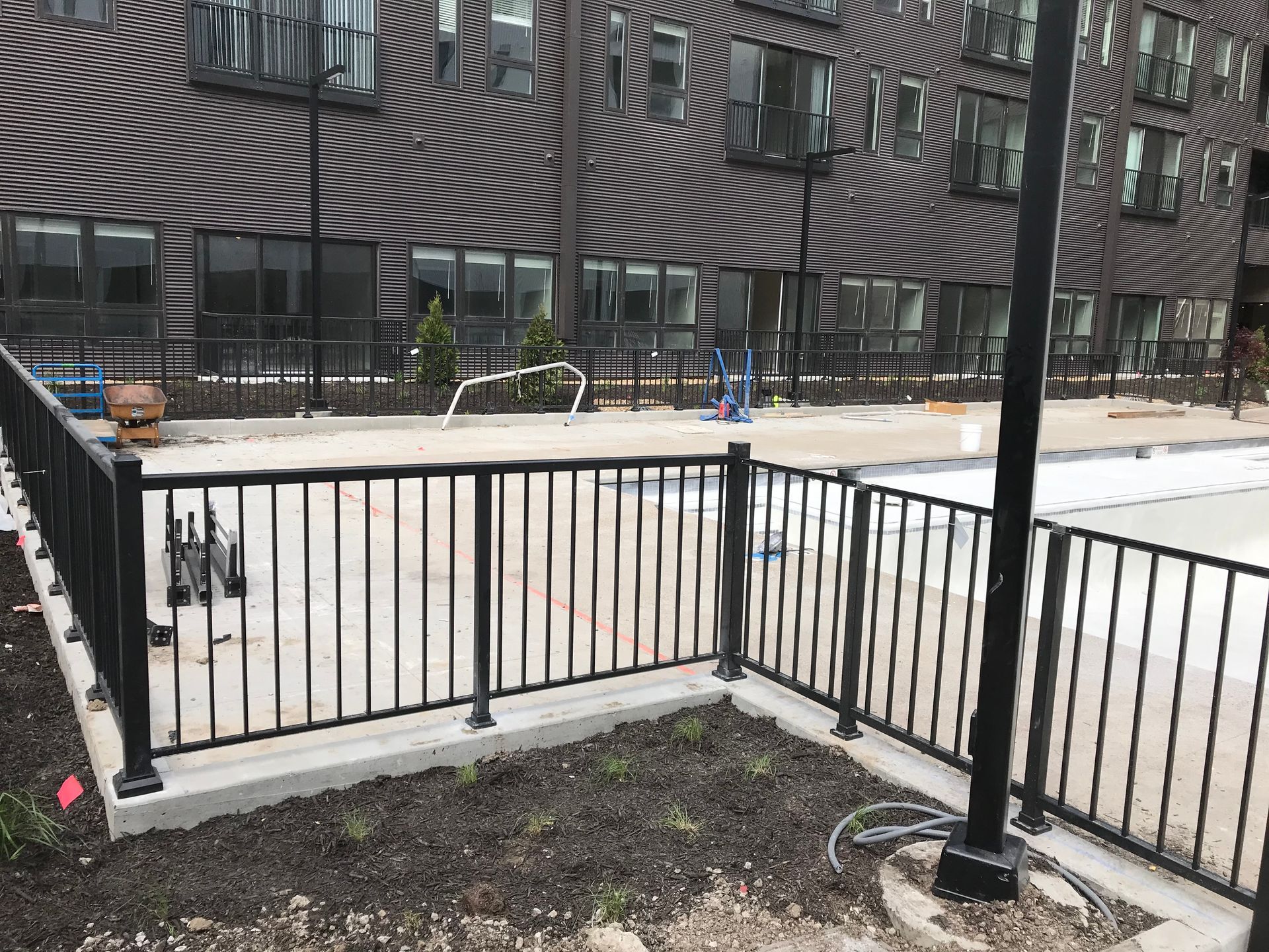 A fence surrounds a swimming pool in front of a building.