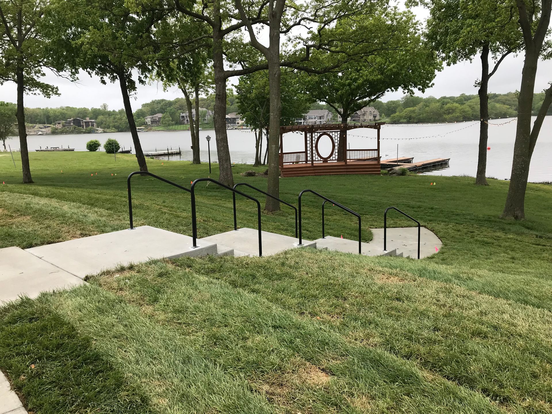 A set of stairs leading up to a gazebo next to a lake with black railings