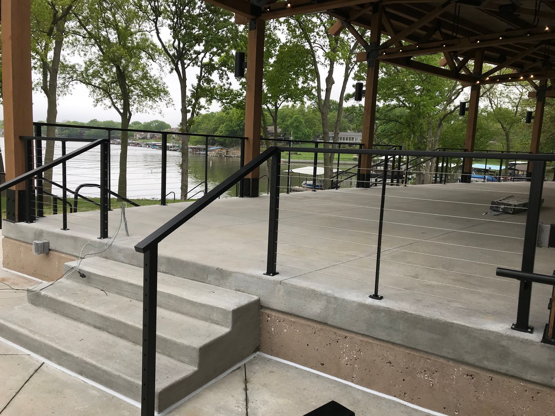 A staircase leading up to a stage with a railing and a view of a lake 
