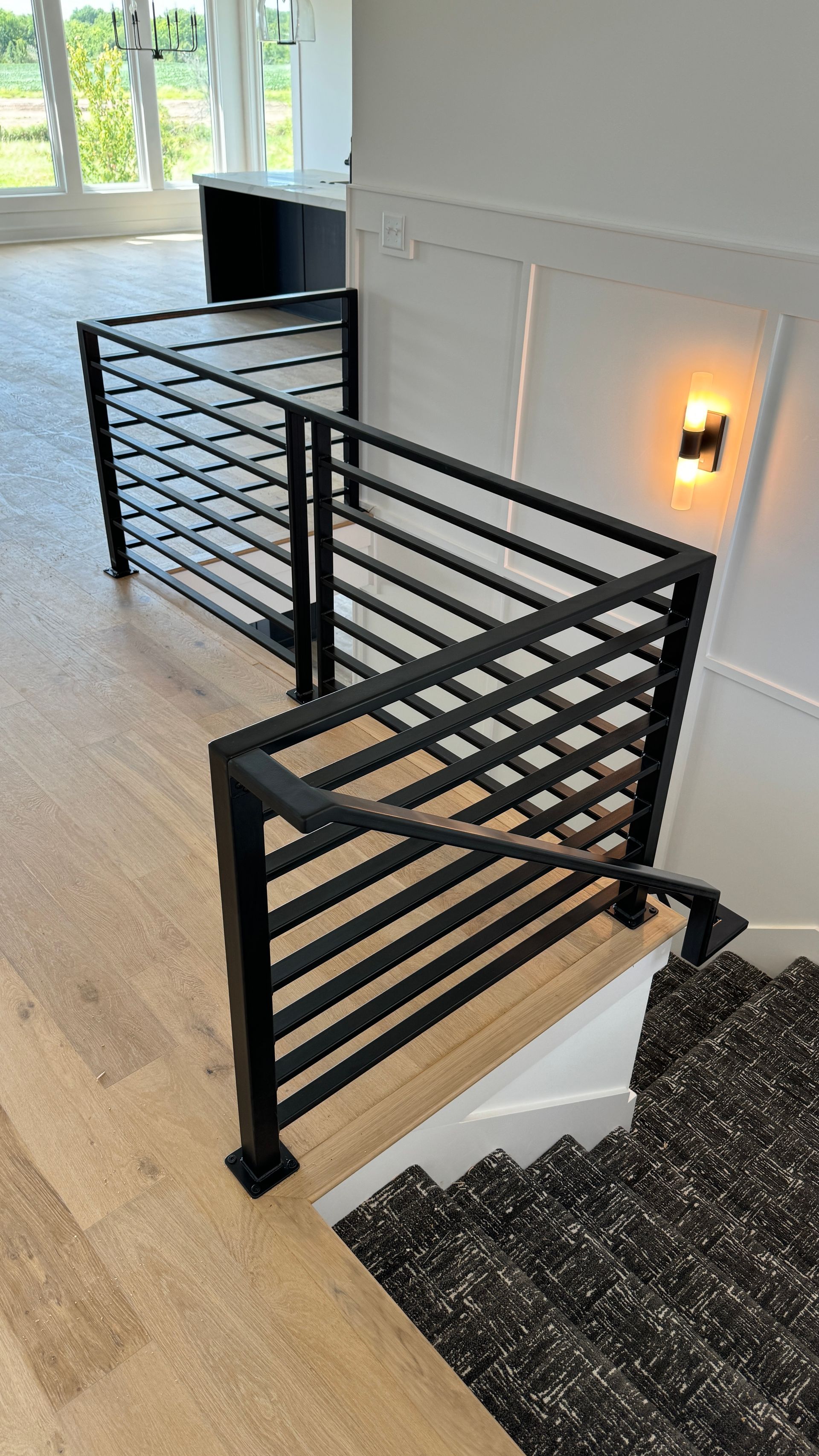 A black railing on a wooden staircase in a house.