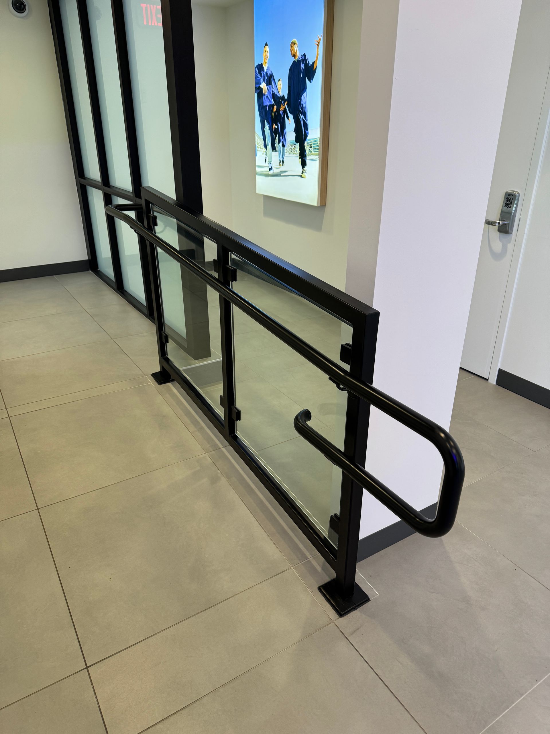 A hallway with a glass railing and a picture on the wall.