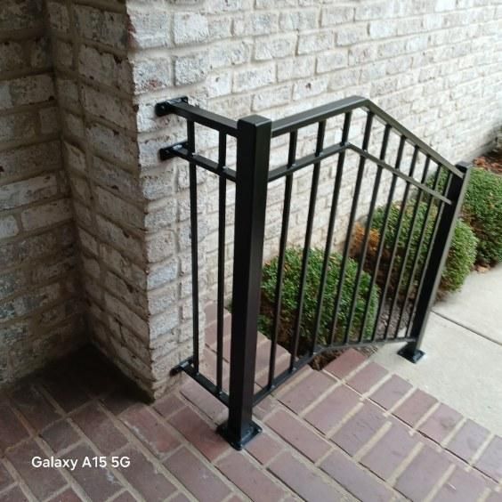 A black railing is shown next to a brick wall