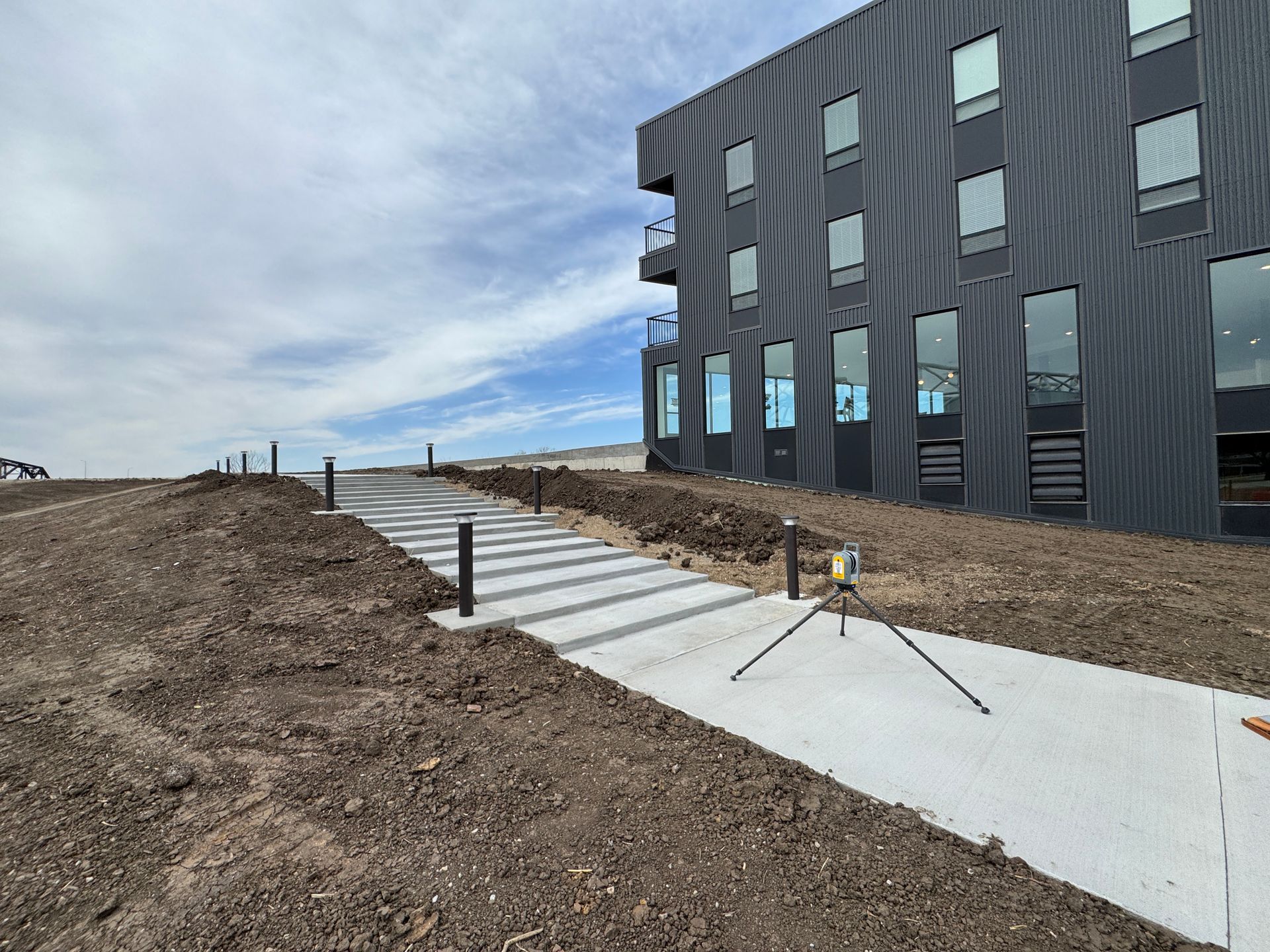 A concrete walkway leading to a large building with a lot of windows.
