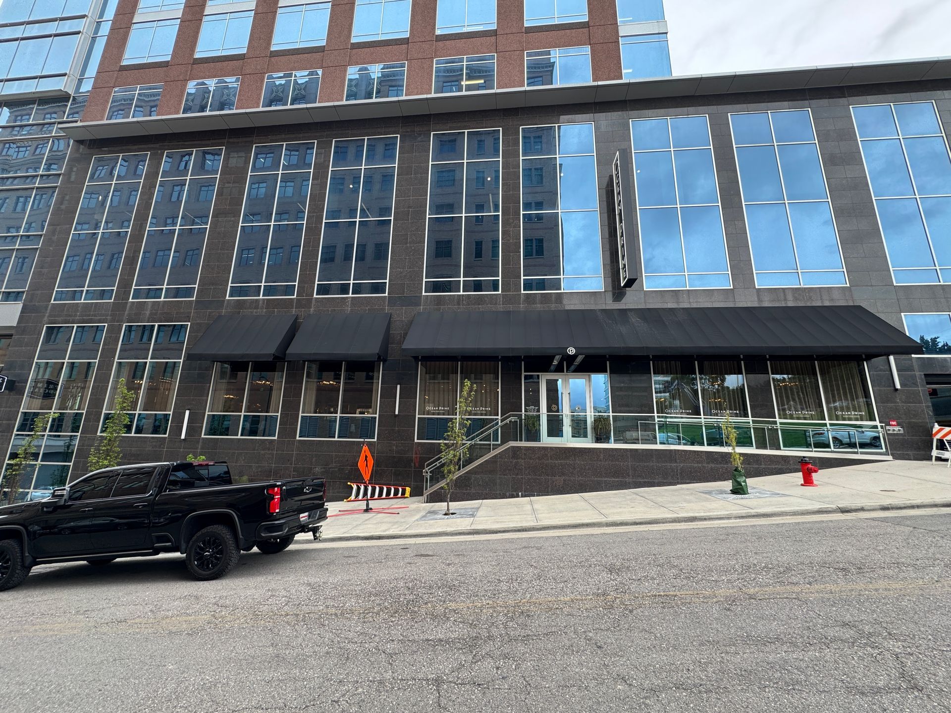 A black truck is parked in front of a large building with custom awnings