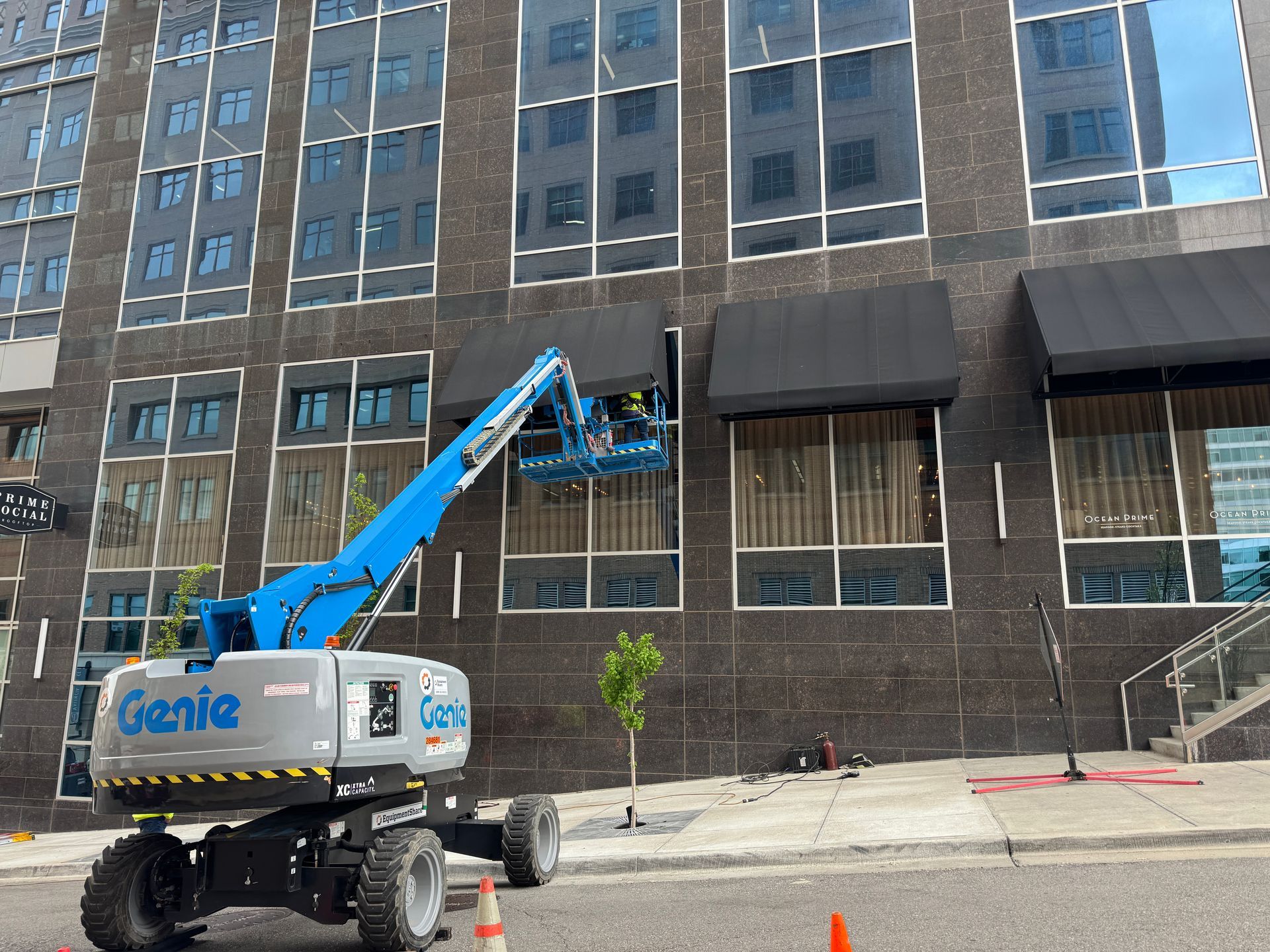 A genie lift is sitting in front of a large building.