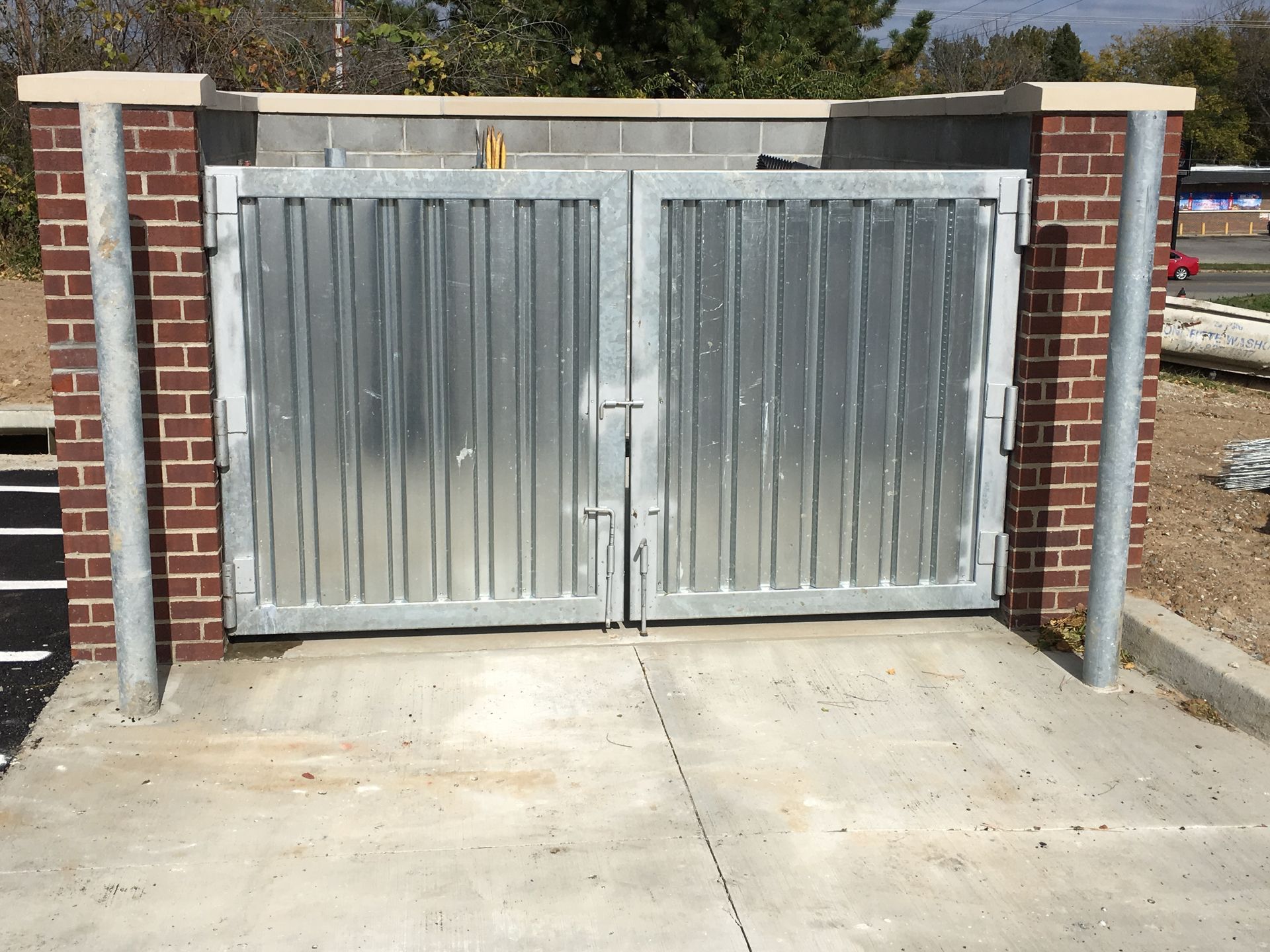 A metal trash gate with a brick wall behind it
