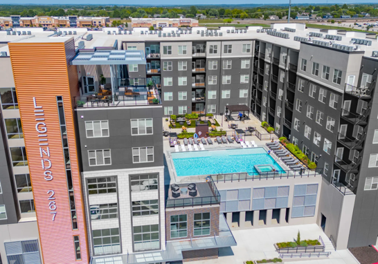 An aerial view of a large apartment building with a swimming pool in the middle.