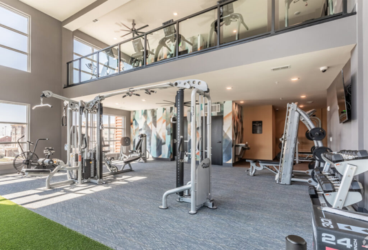 A large gym with a lot of equipment and a balcony.