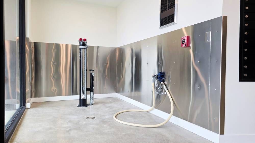 A room with stainless steel walls and a hose attached to the wall.