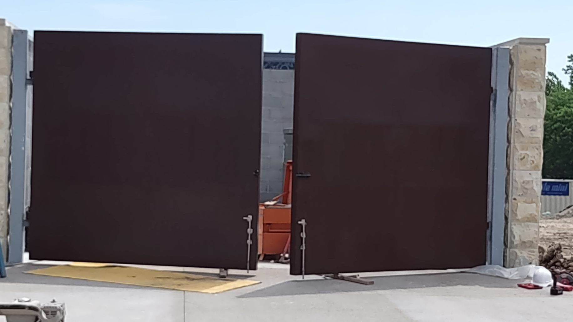 A pair of brown metal gates are open on a concrete surface.