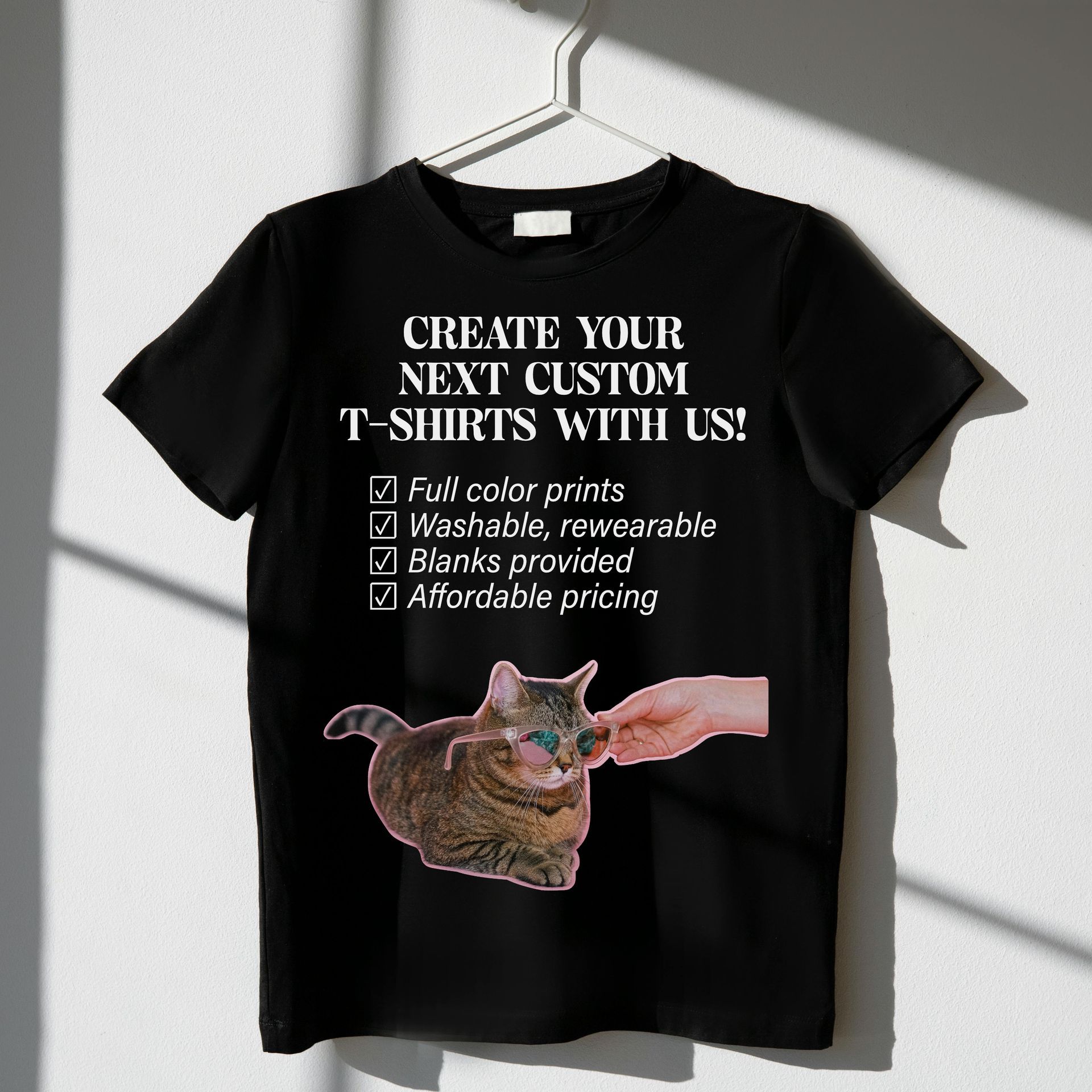 Black t-shirt with text advertising custom shirts, a cat image, and a hand petting it.