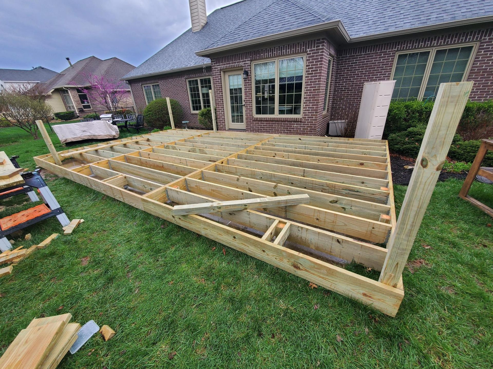 A wooden deck is being built in the backyard of a house.