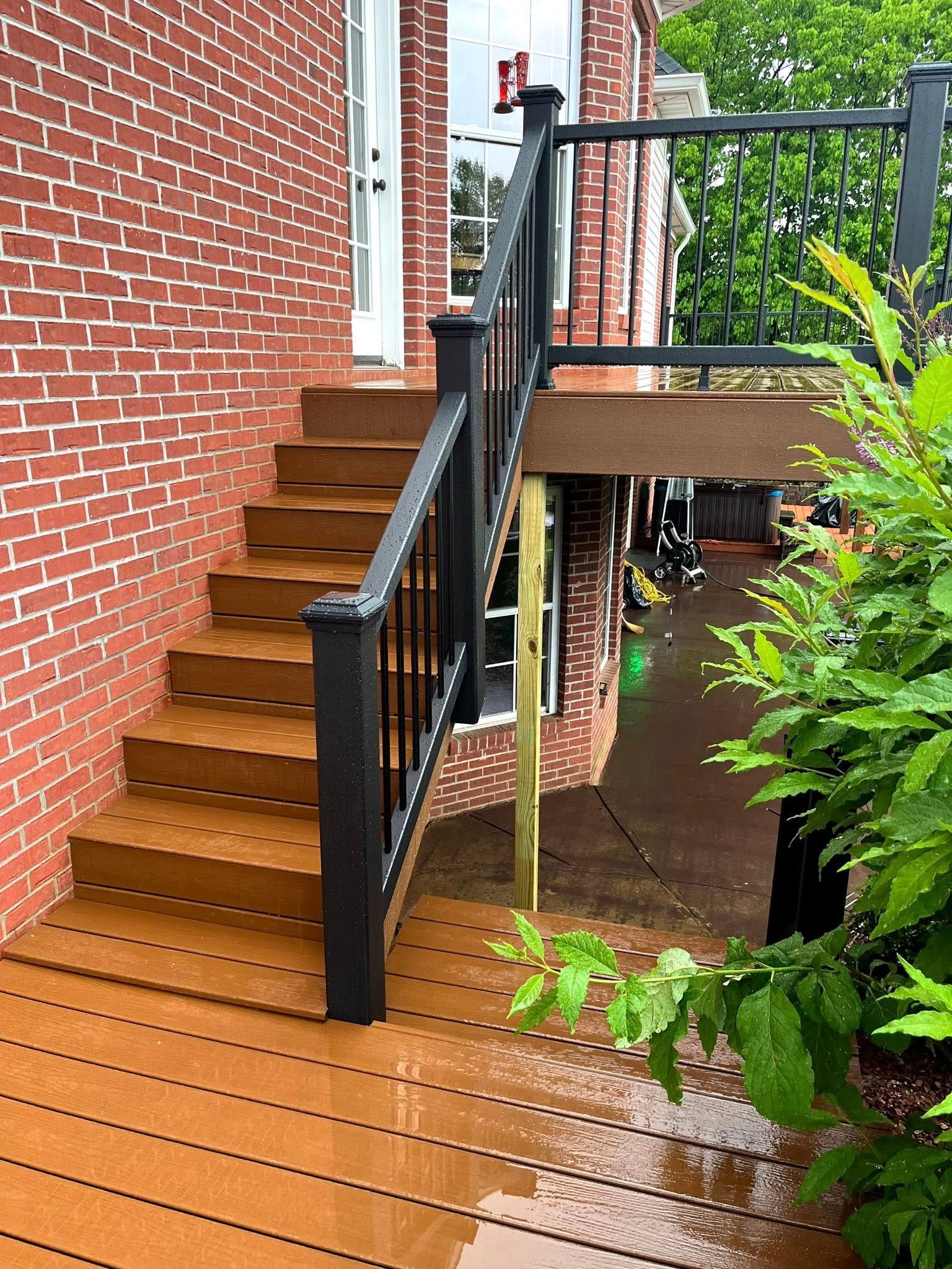 A wooden deck with stairs leading up to a brick building.