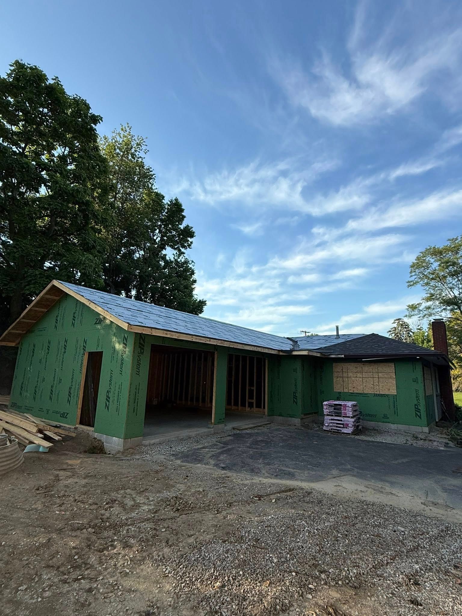 A house is being built with green insulation and a roof.