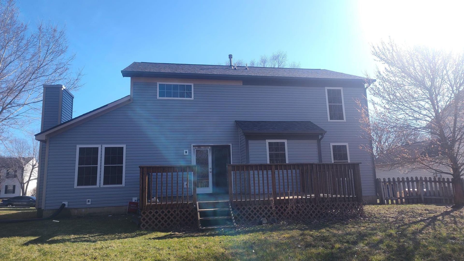 The back of a house with a deck and a blue sky in the background.