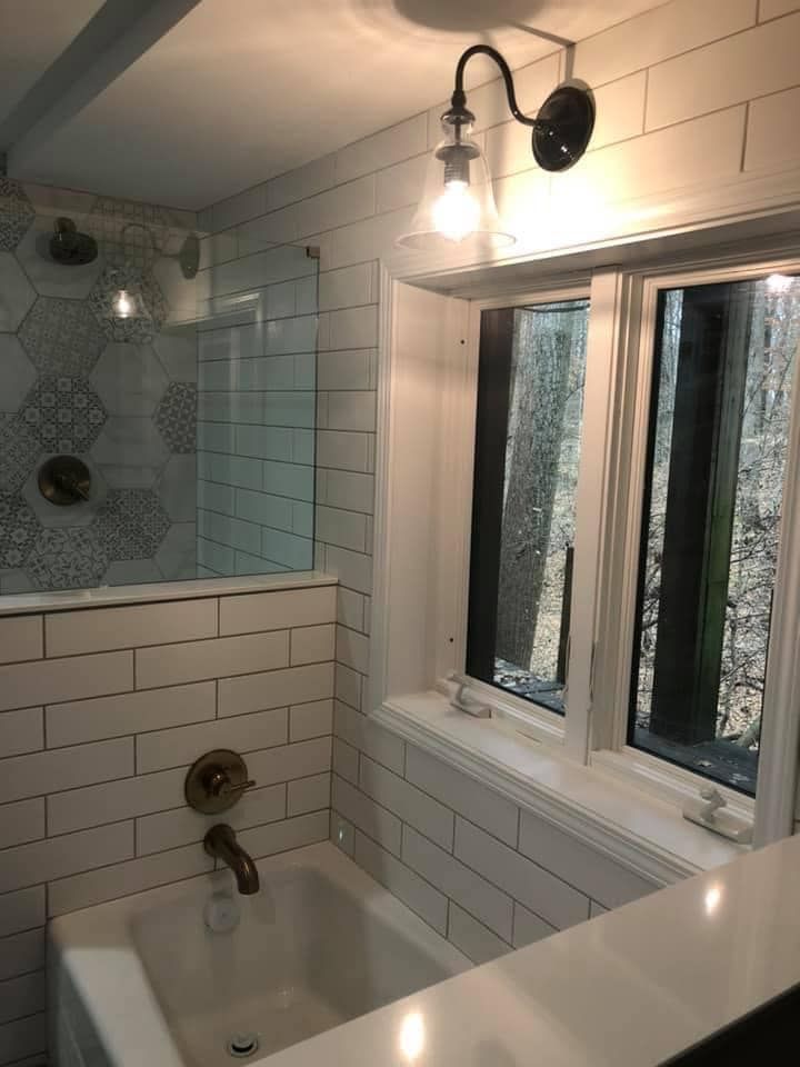 A bathroom with a tub , shower and window