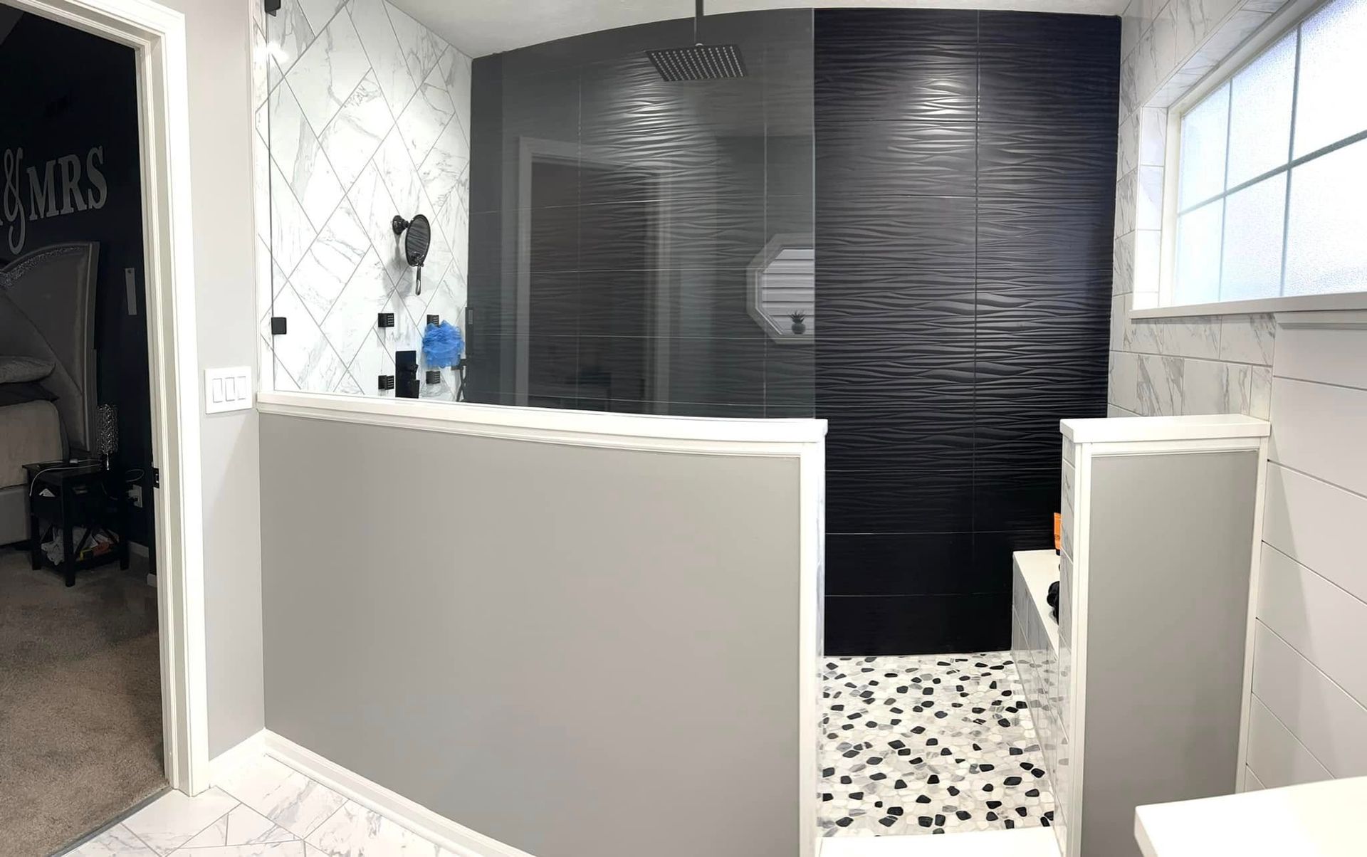 A bathroom with black and white tiles and a walk in shower.