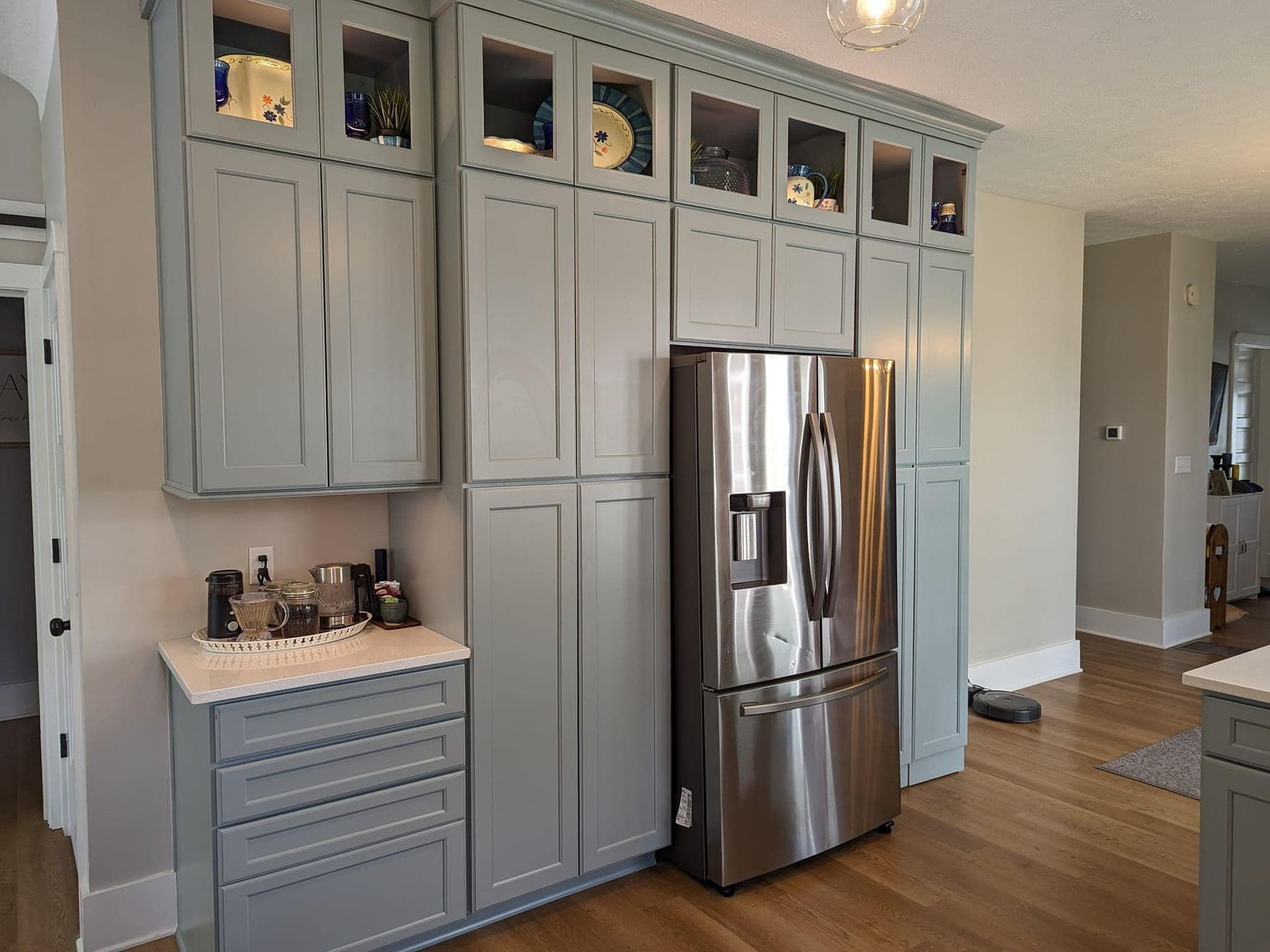 A kitchen with gray cabinets and a stainless steel refrigerator.