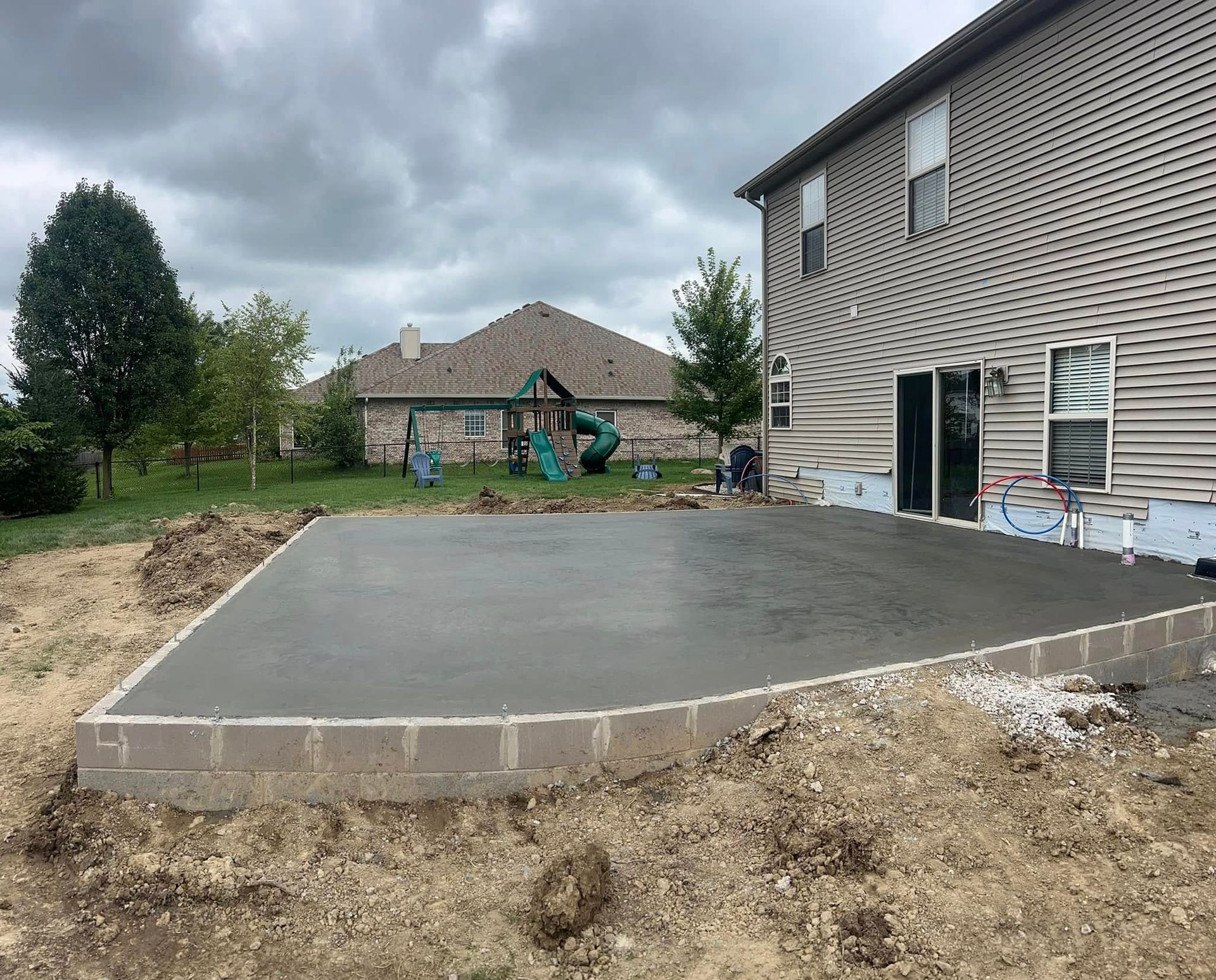 A concrete patio is being built in front of a house.