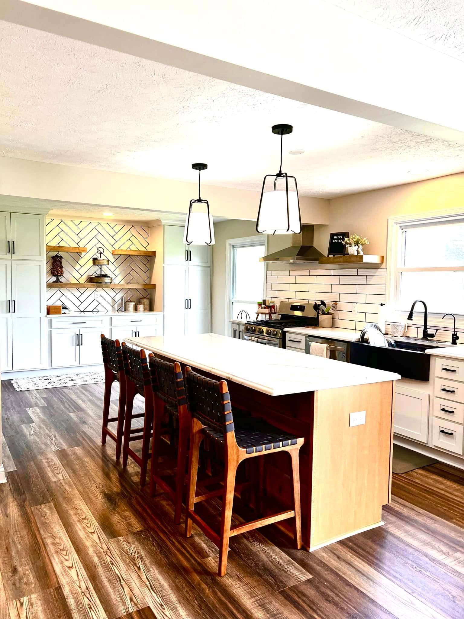 A kitchen with a large island and stools in it.