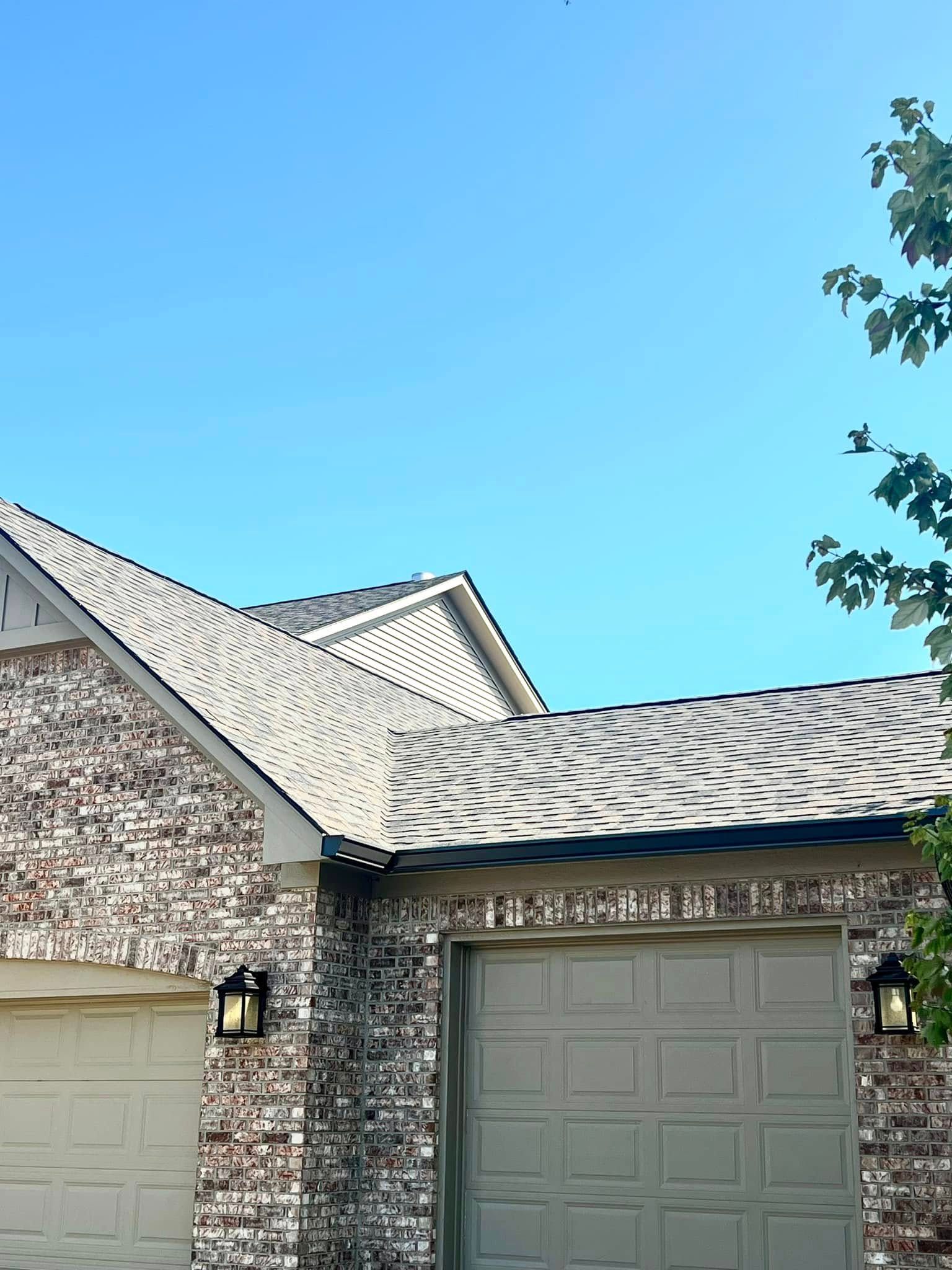A brick house with a garage door and a blue sky in the background
