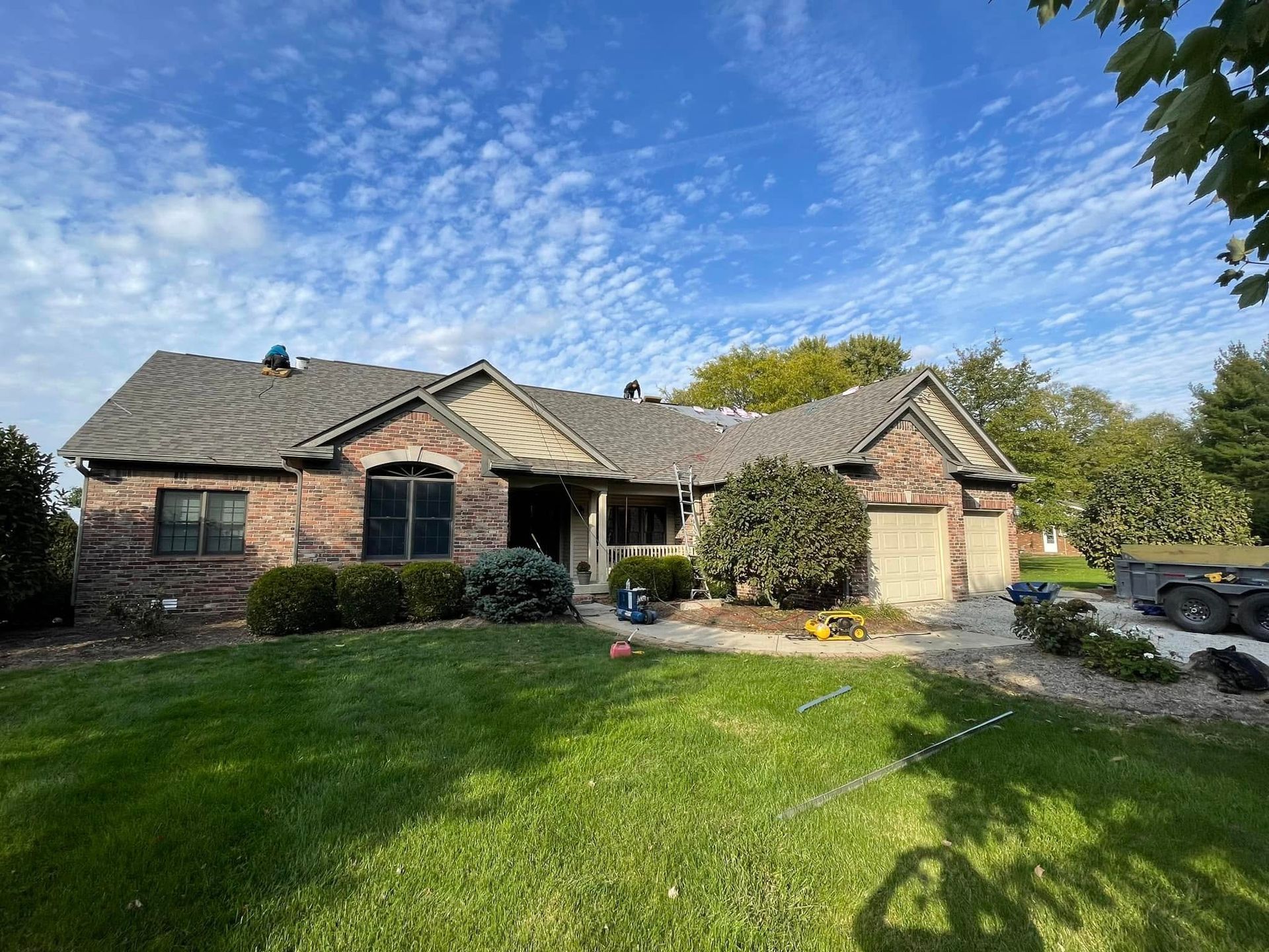 A brick house with a gray roof and a large lawn in front of it.