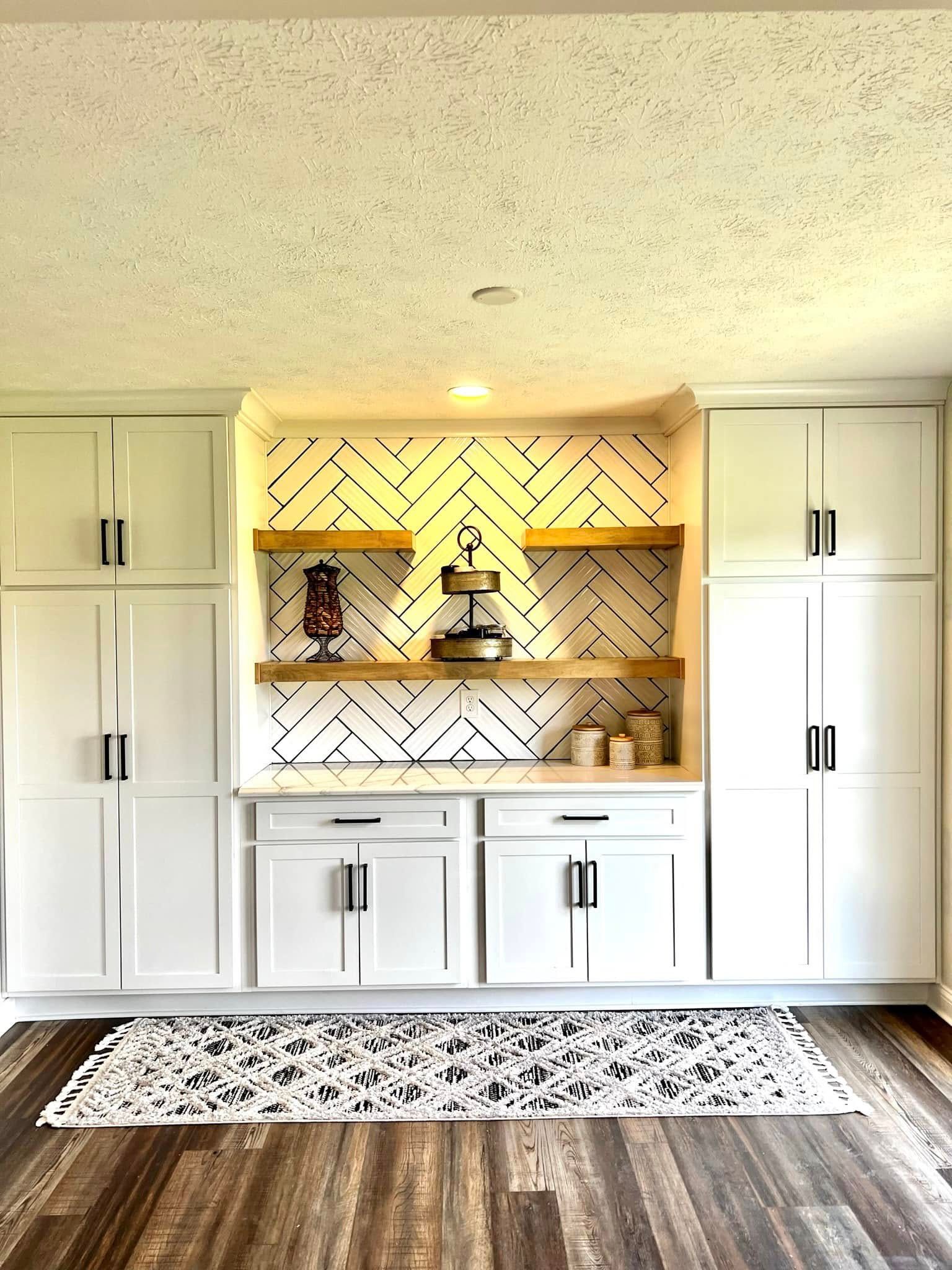 A kitchen with white cabinets , wooden shelves , and a rug.