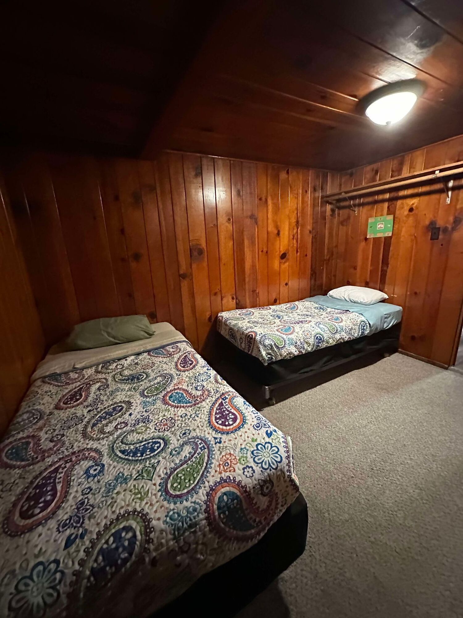 A bedroom with two beds and wooden walls.