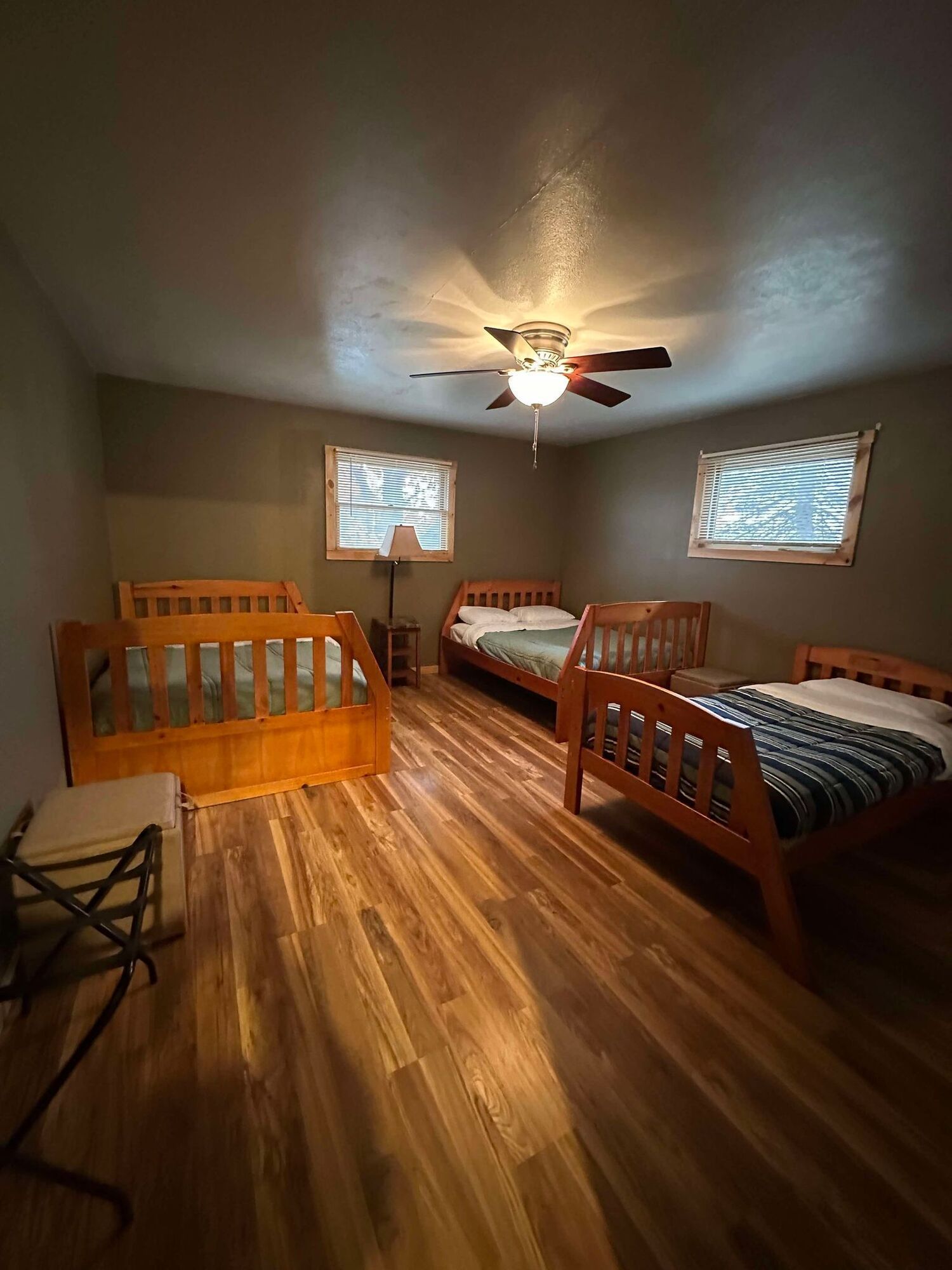 A bedroom with three beds and a ceiling fan.