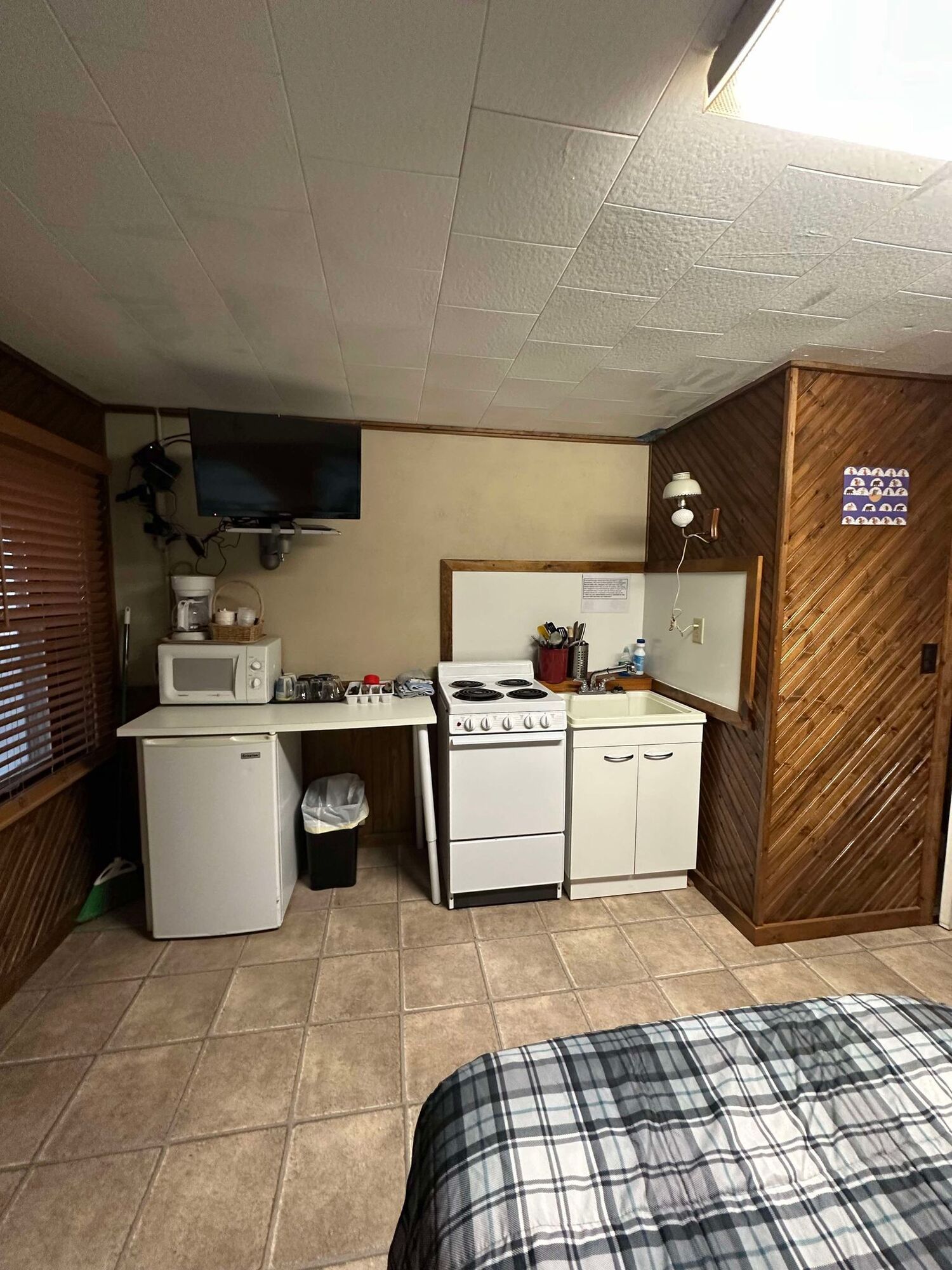 A bedroom with a stove , refrigerator , microwave and a bed.