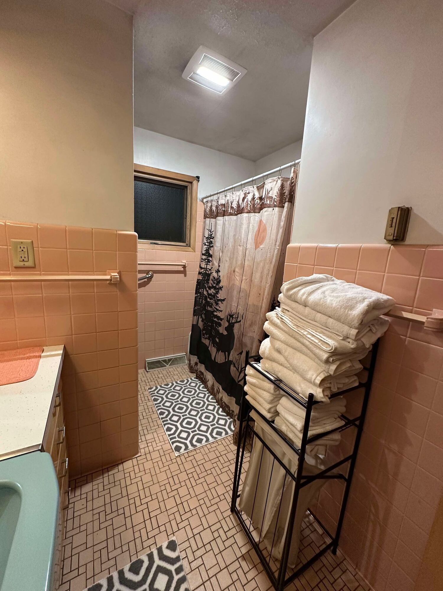 A bathroom with a shower curtain and a stack of towels on a rack.
