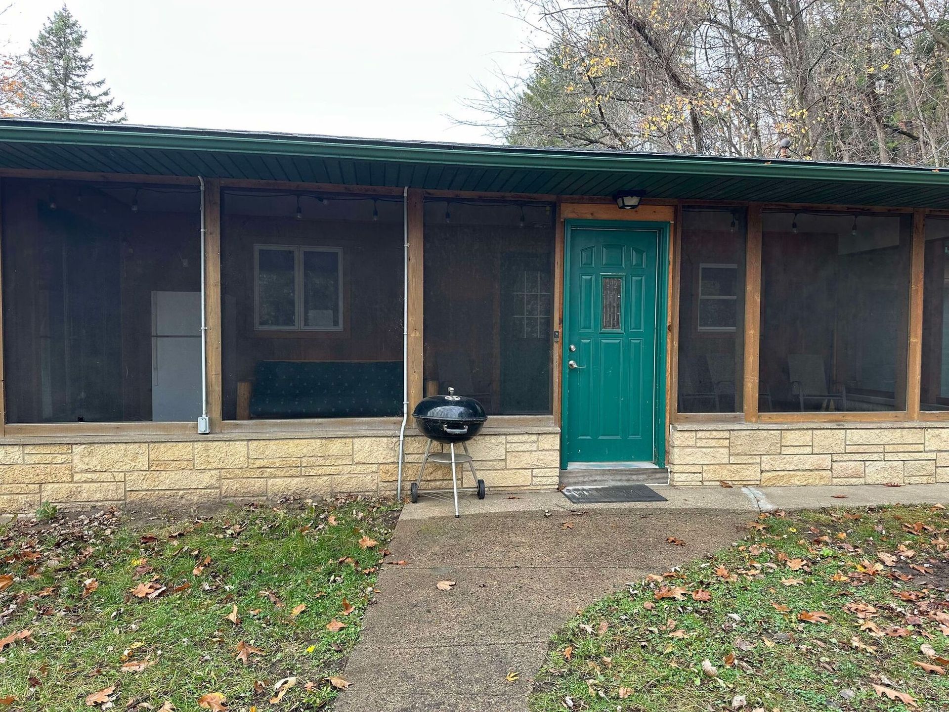 A house with a screened in porch and a green door.