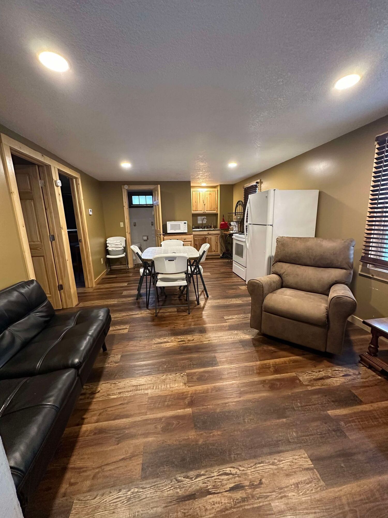 A living room with a couch , chair , table and refrigerator.