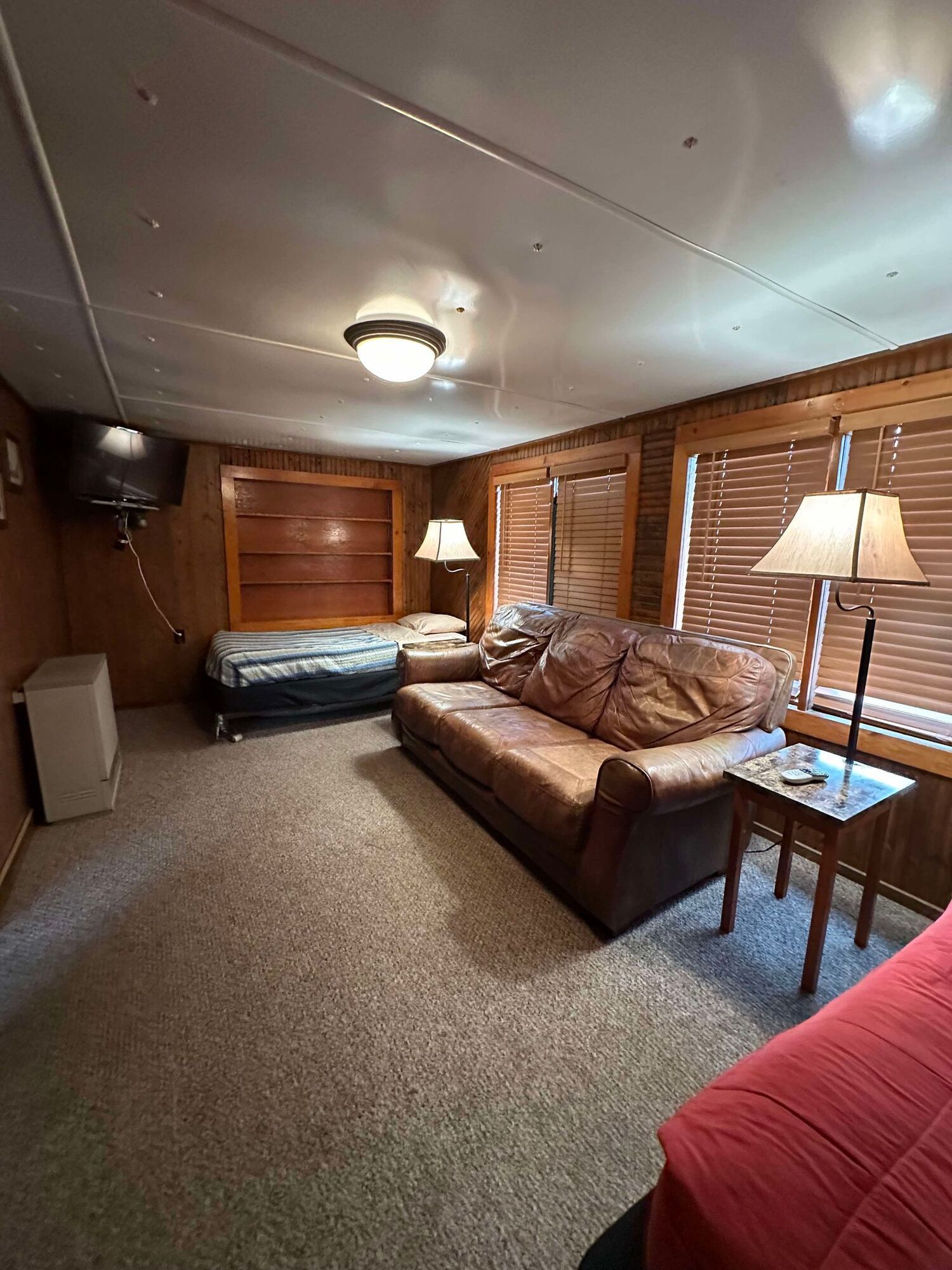 A living room with a couch , bed , lamps and a television.