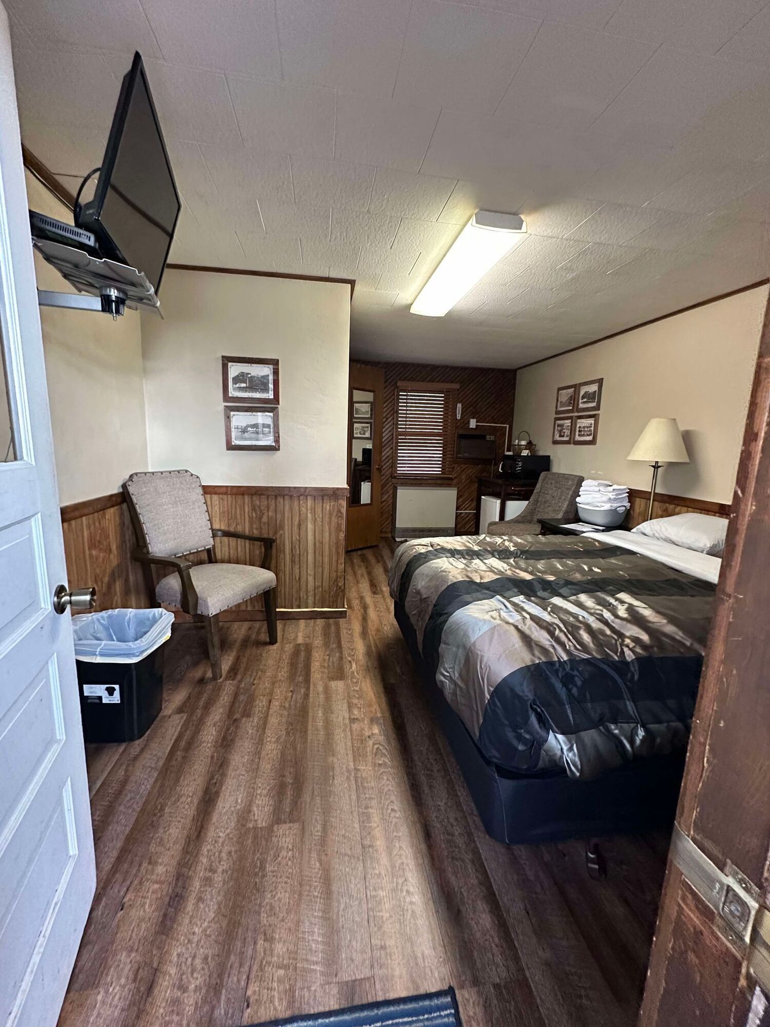 A hotel room with two beds , a chair , and a flat screen tv.