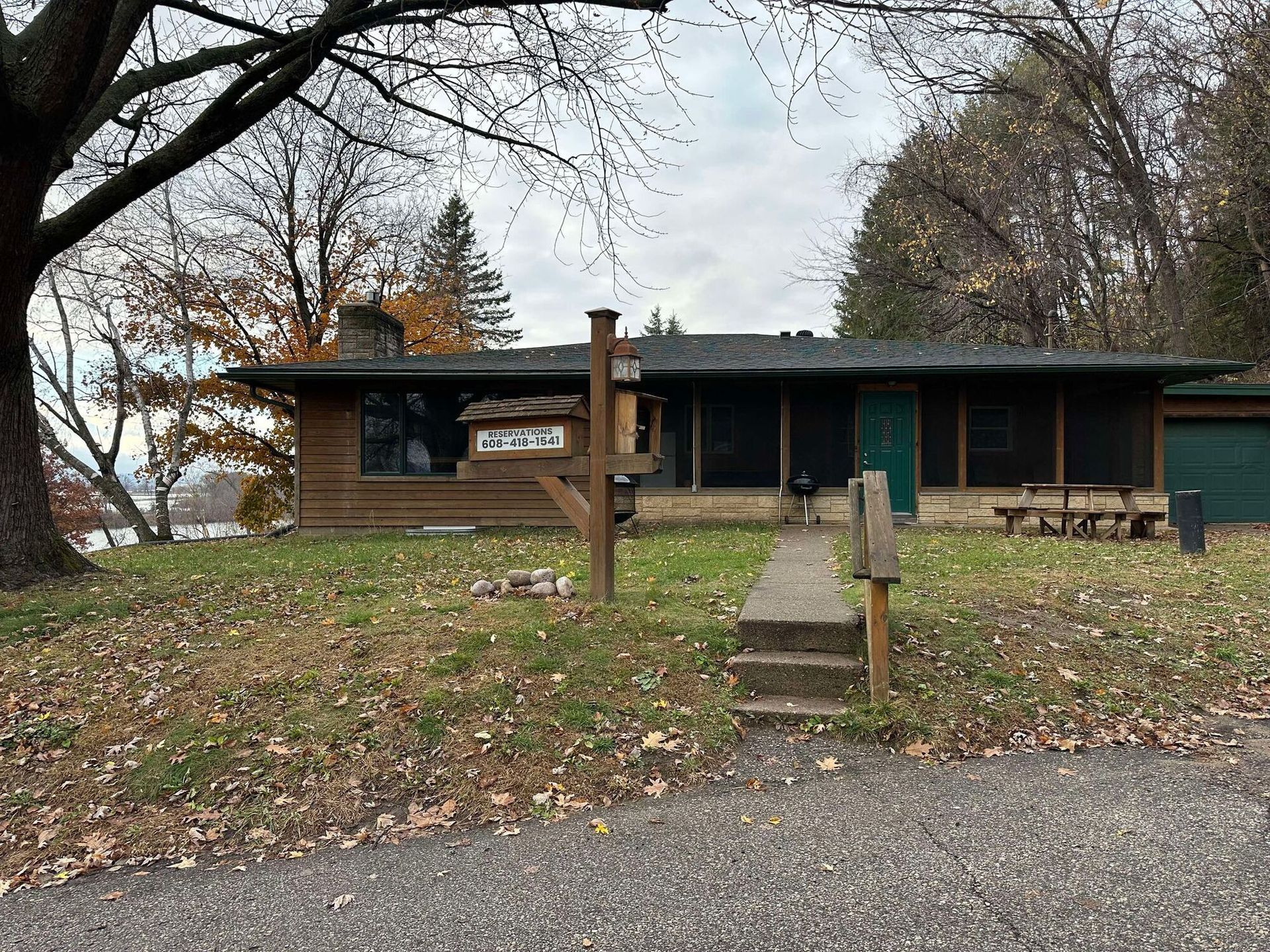 A house is sitting on top of a grass covered field next to a tree.